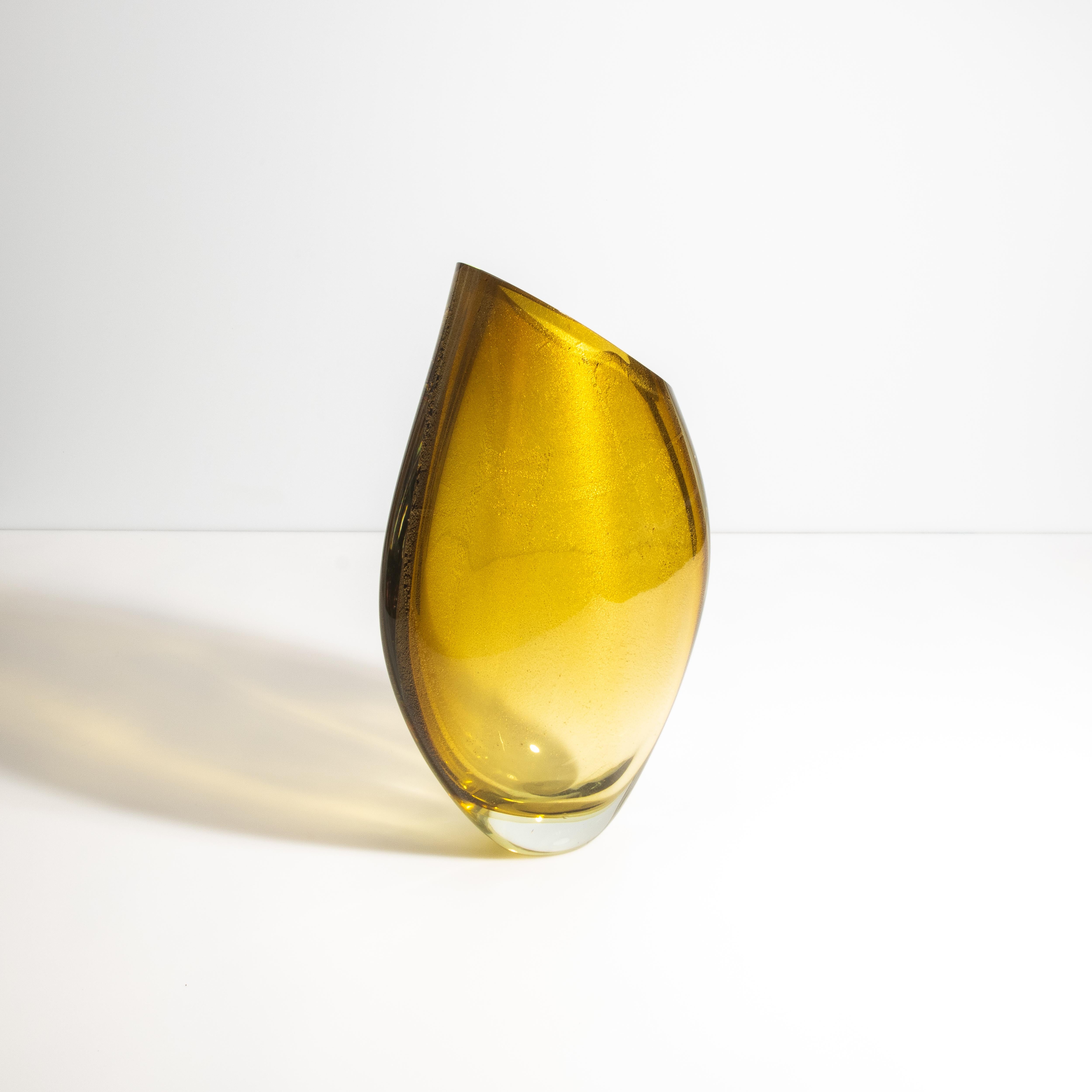 Questo squisito vaso con riflessi d'oro a 24 carati porta nel tuo spazio un tocco di campagna italiana illuminata dal sole. La tonalità ambra dorata del vaso, che ricorda le calde sfumature che si vedono nei vigneti della Toscana durante la stagione