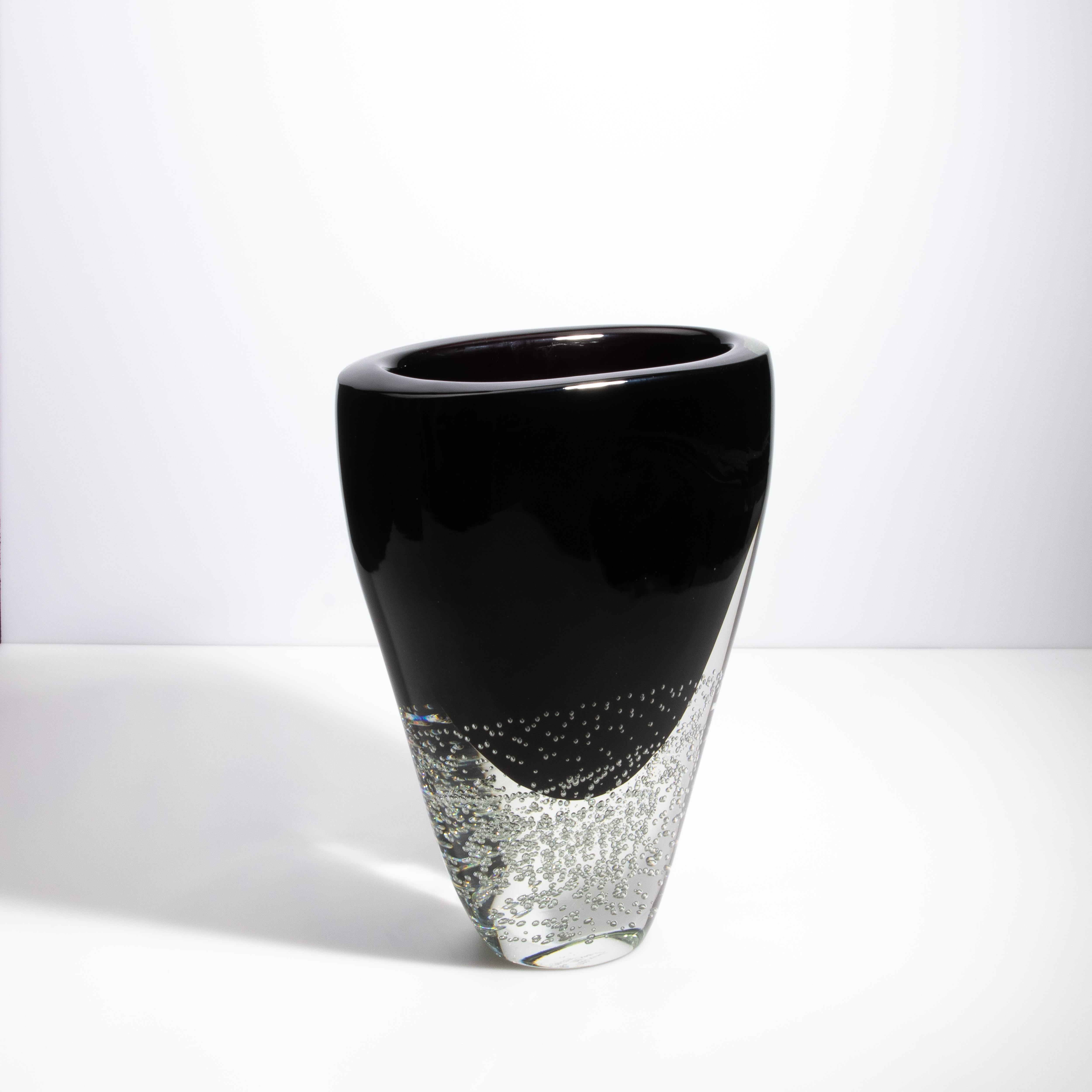 Questo alto vaso di Murano soffiato a mano, realizzato con la squisita tecnica del Sommerso, è un'opera d'arte ipnotica che incarna l'eleganza senza tempo dell'arte vetraria veneziana. Il vaso è caratterizzato da un'accattivante combinazione di
