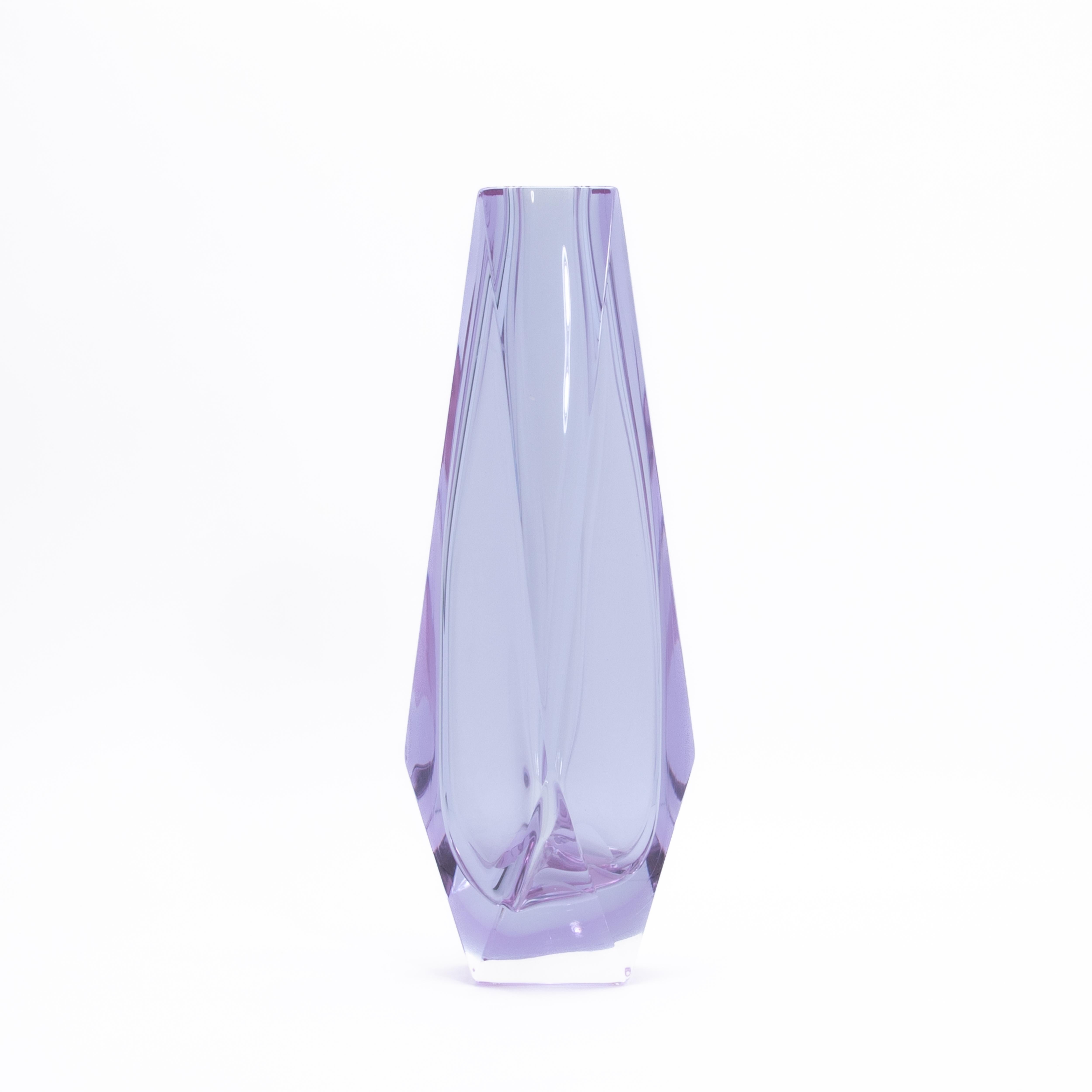 Questo squisito vaso è un esempio accattivante dell'arte del vetro di Murano, meticolosamente lavorato a mano per irradiare raffinatezza ed eleganza moderna. La tonalità traslucida della lavanda mescola delicatamente i toni del lilla con una sottile