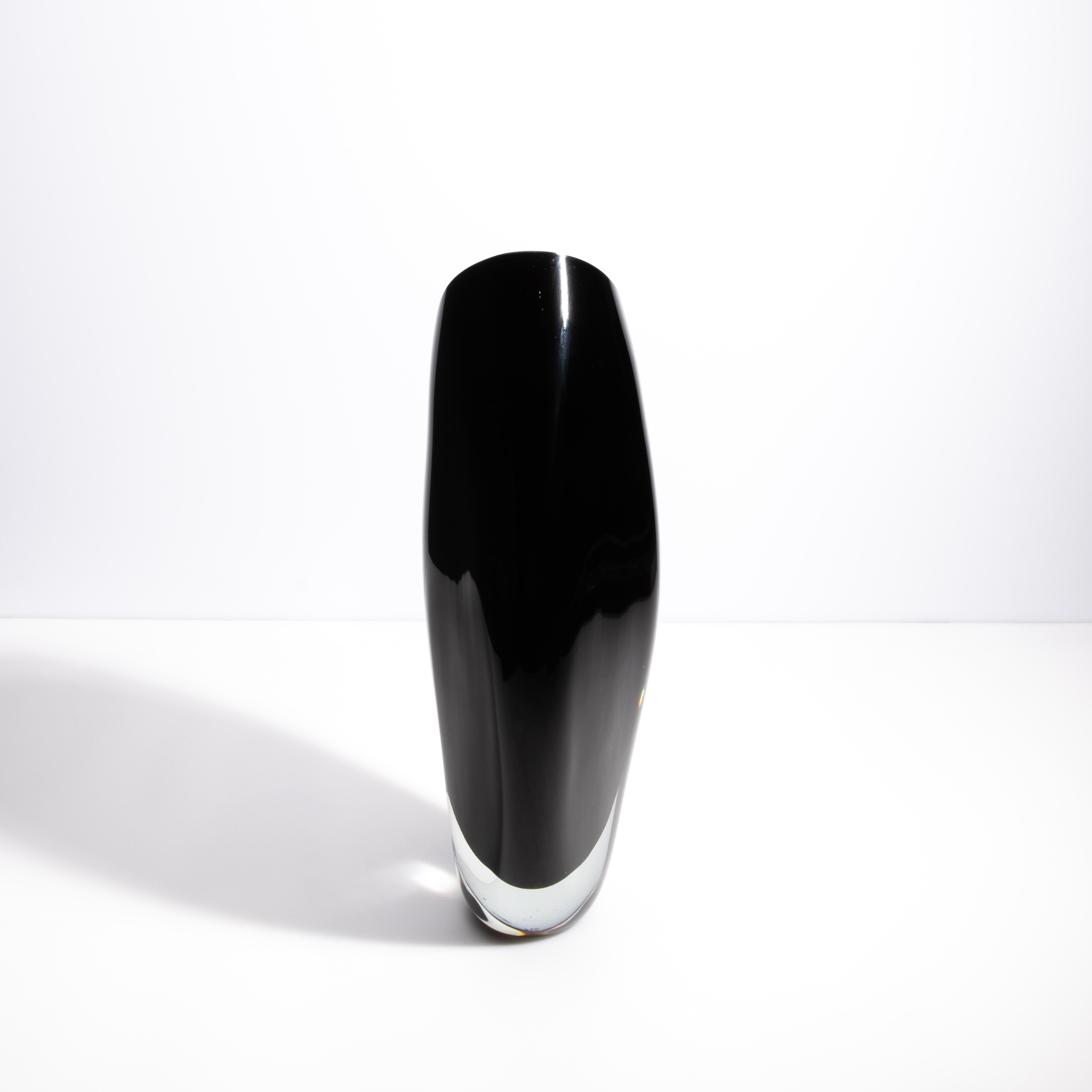Questo elegante vaso in vetro di Murano incarna la raffinatezza e l'arte senza tempo dei vetrai veneziani. La sua tonalità nera profonda, in contrasto con i bordi in vetro cristallino, evoca un senso di lusso moderno. La silhouette elegante e