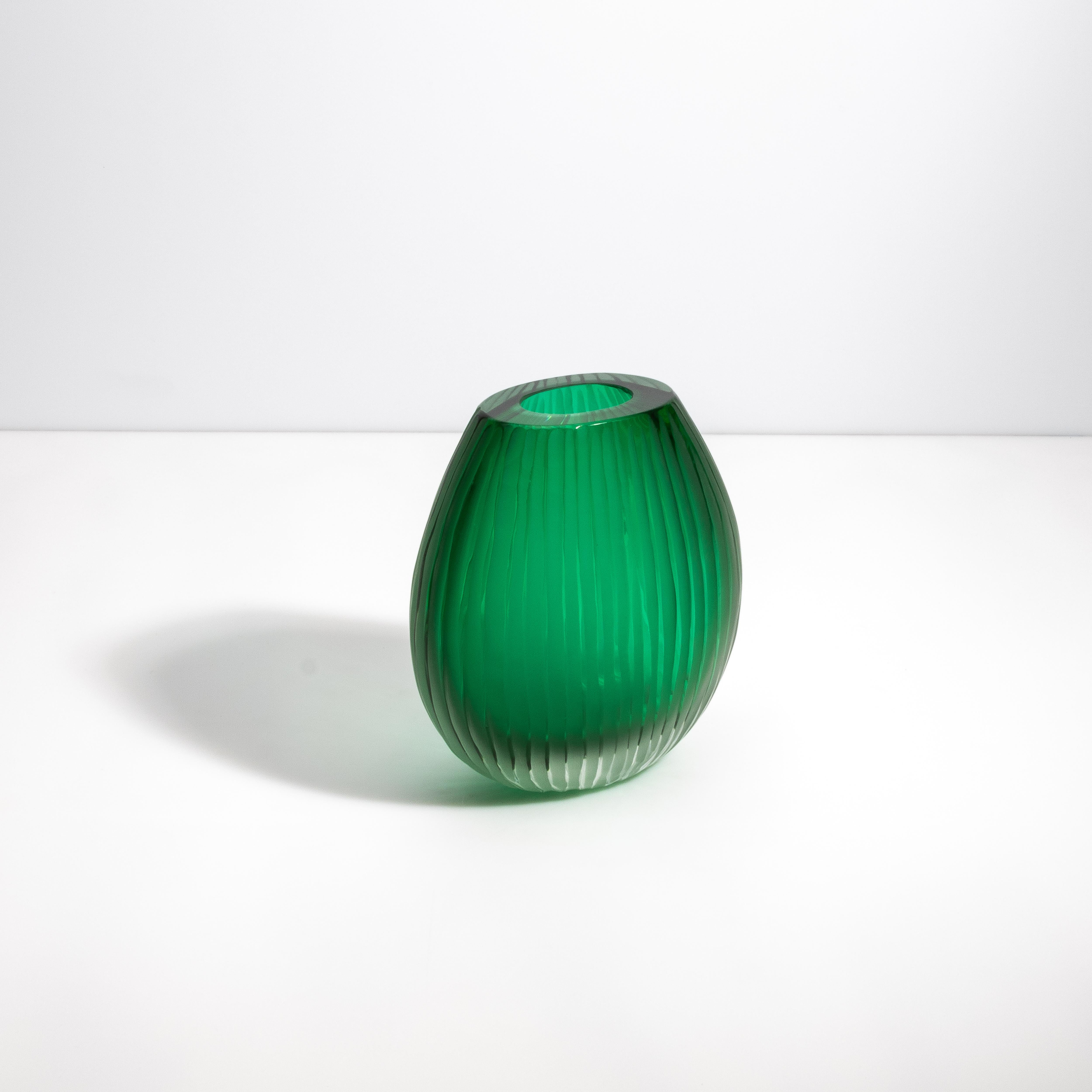 This eye-catching Murano vase stands as a testament to the exquisite art of Venetian glassblowing. With its deep emerald core that descends into a clear base through its organic groves and contours, this piece is not just a vase but a statement of