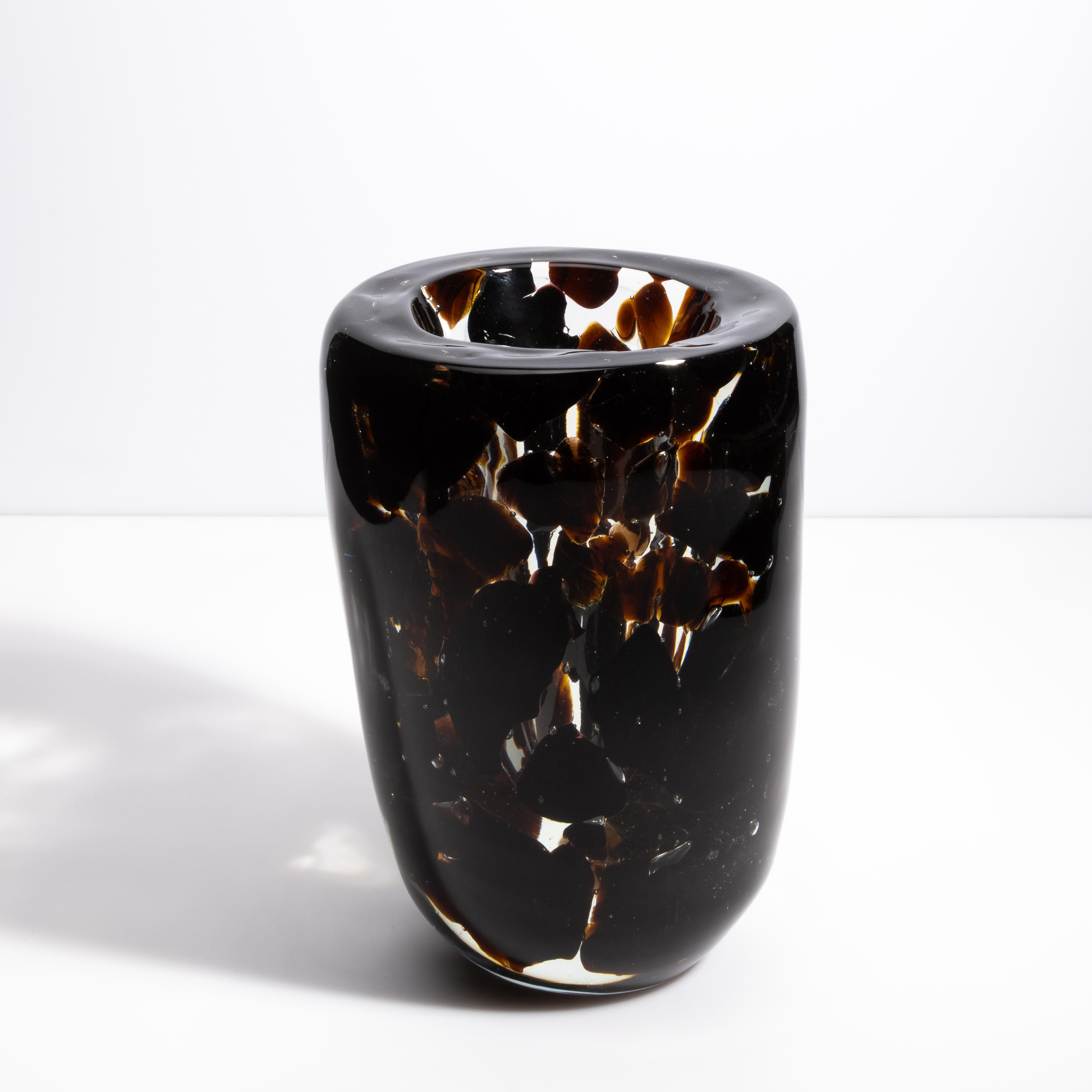 Voici un captivant vase en verre de Murano soufflé à la main, incarnation exquise de l'art et de l'élégance vénitiens. Ce superbe vase présente un design marbré unique avec des tons riches et profonds d'onyx entrecoupés d'accents ambrés et clairs