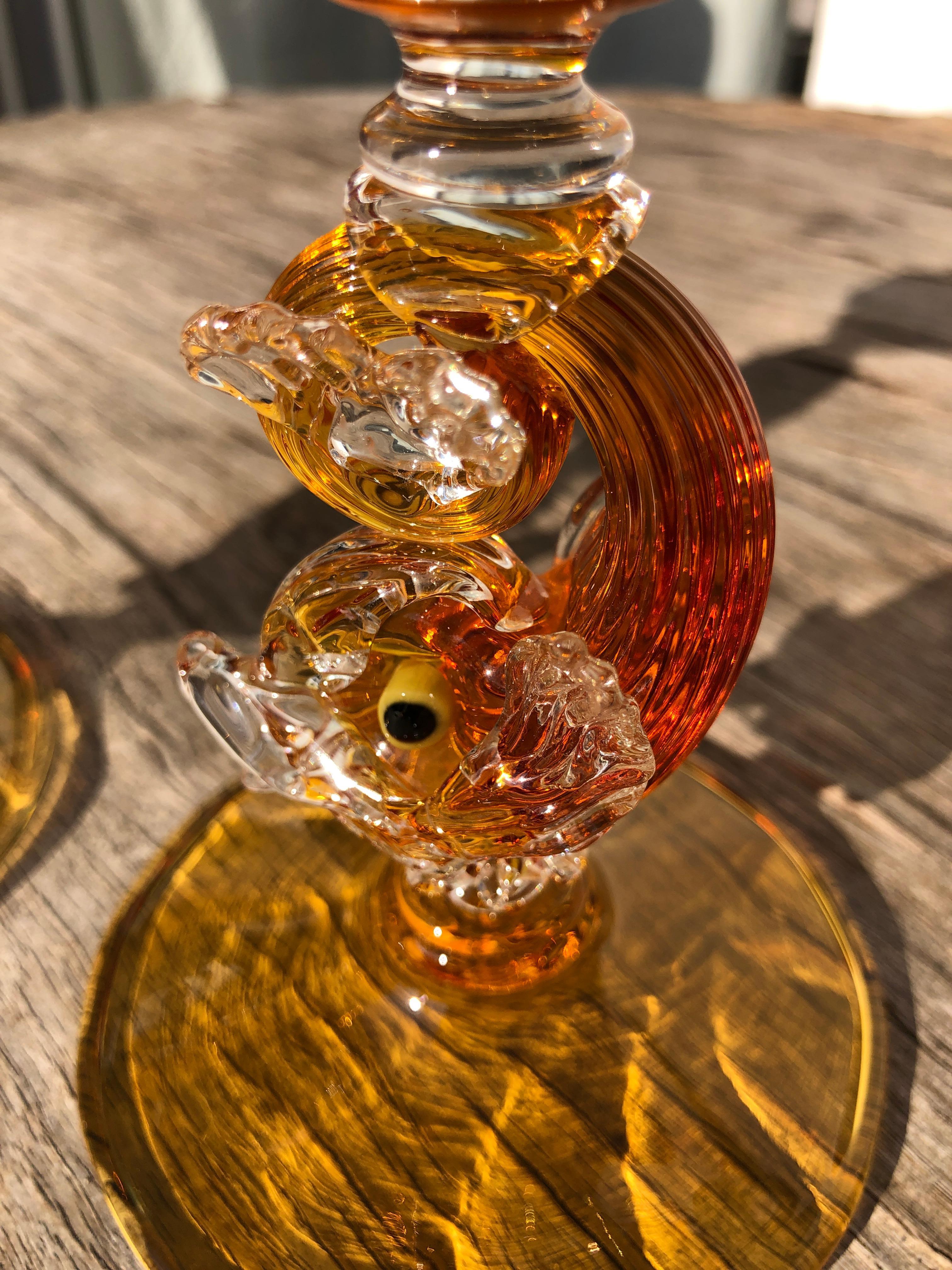 This pair of hand blown candlesticks are made of a very unusual amber color with a charming dolphin connector. Made by the master glassblowing firm of Antonio Salviati, the workmanship speaks for itself. Figural dolphins add just the perfect amount