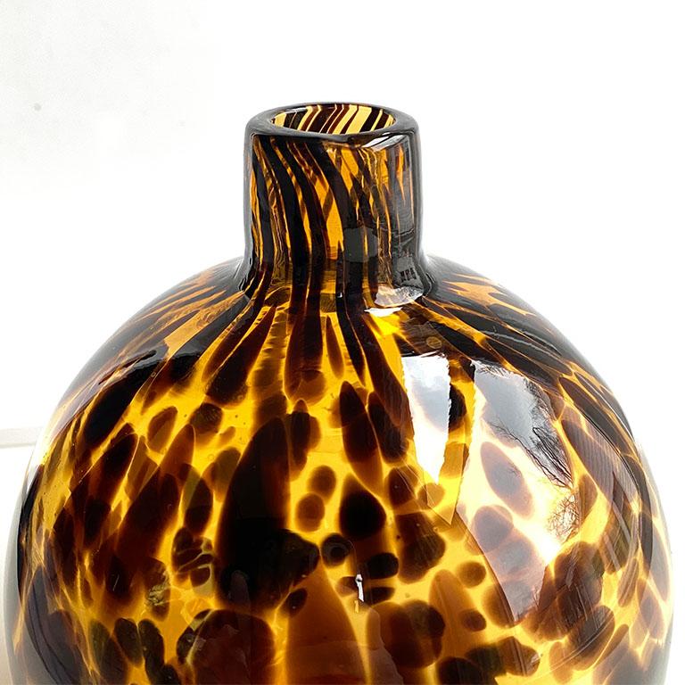 A small hand-blown Murano tiger glass balloon vase in a variety of browns. This vase reminds us of the colors of tortoiseshell and would be a beautiful addition to any side table or nightstand. Or even a patio table while entertaining.