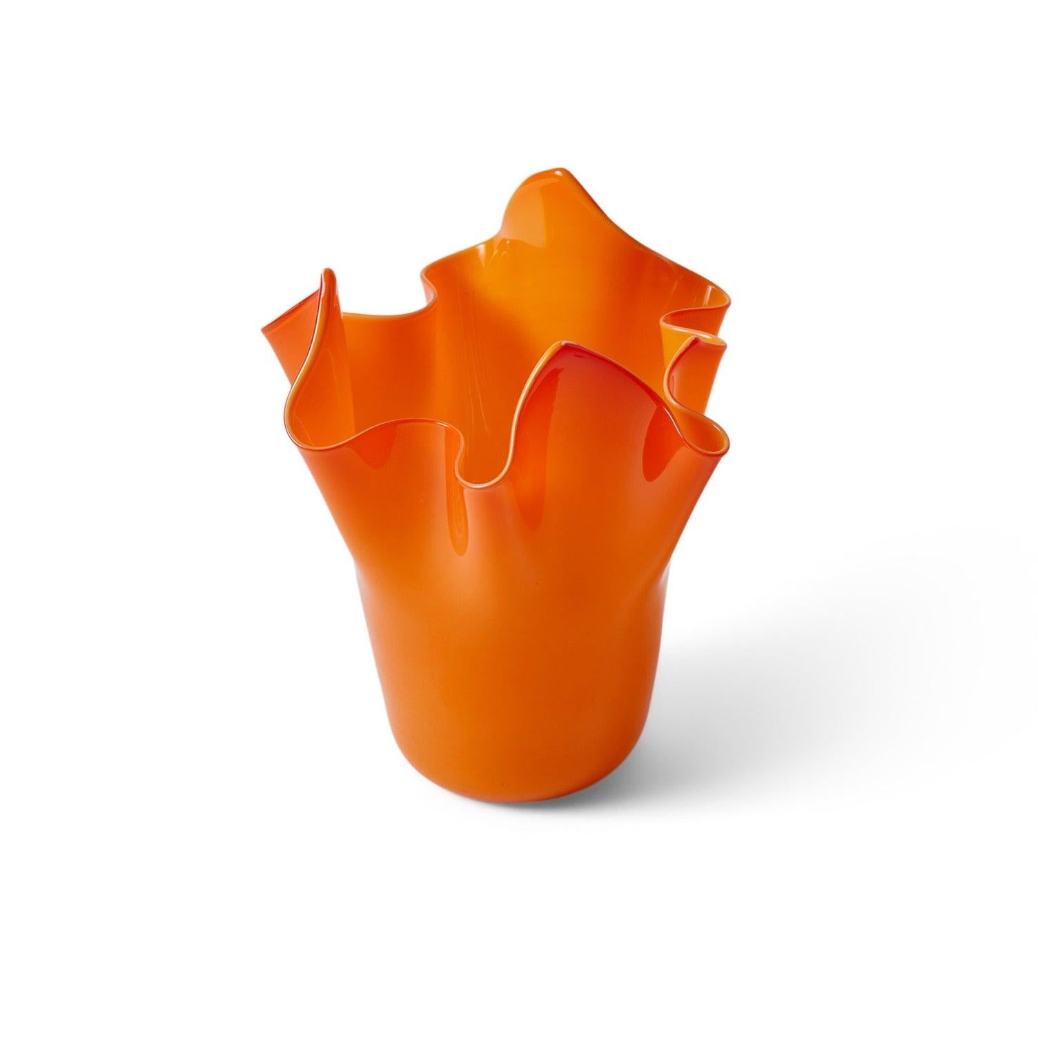 Un vaso in vetro arancione soffiato a mano libera.