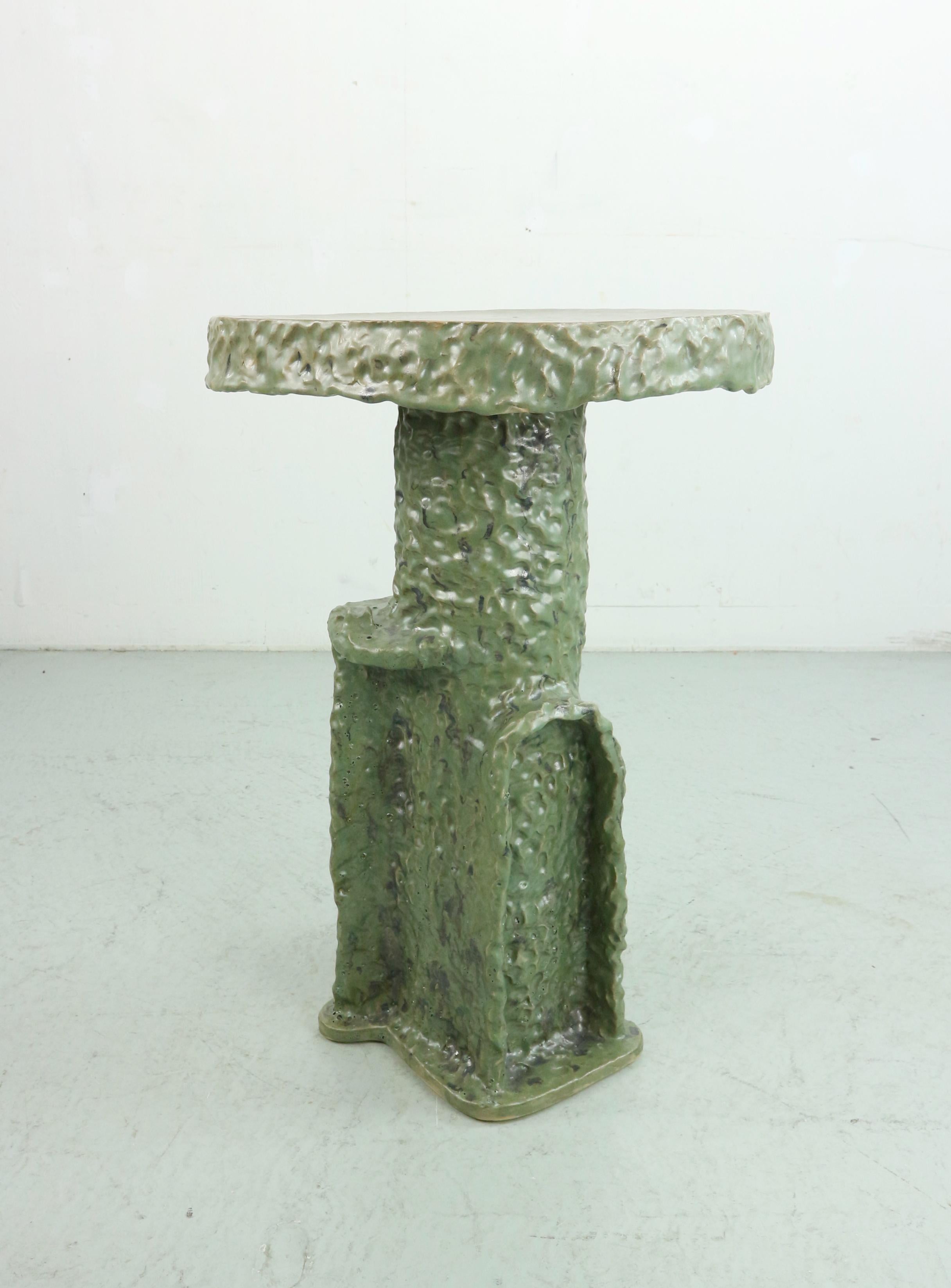 Hand-build stoneware tall side table, leaving fingerprints of the artist to emphasise on the handmade character. 

The piece is a one-off and signed by the artist.

The stoneware side table can be used outside and has a bold  green glaze with black