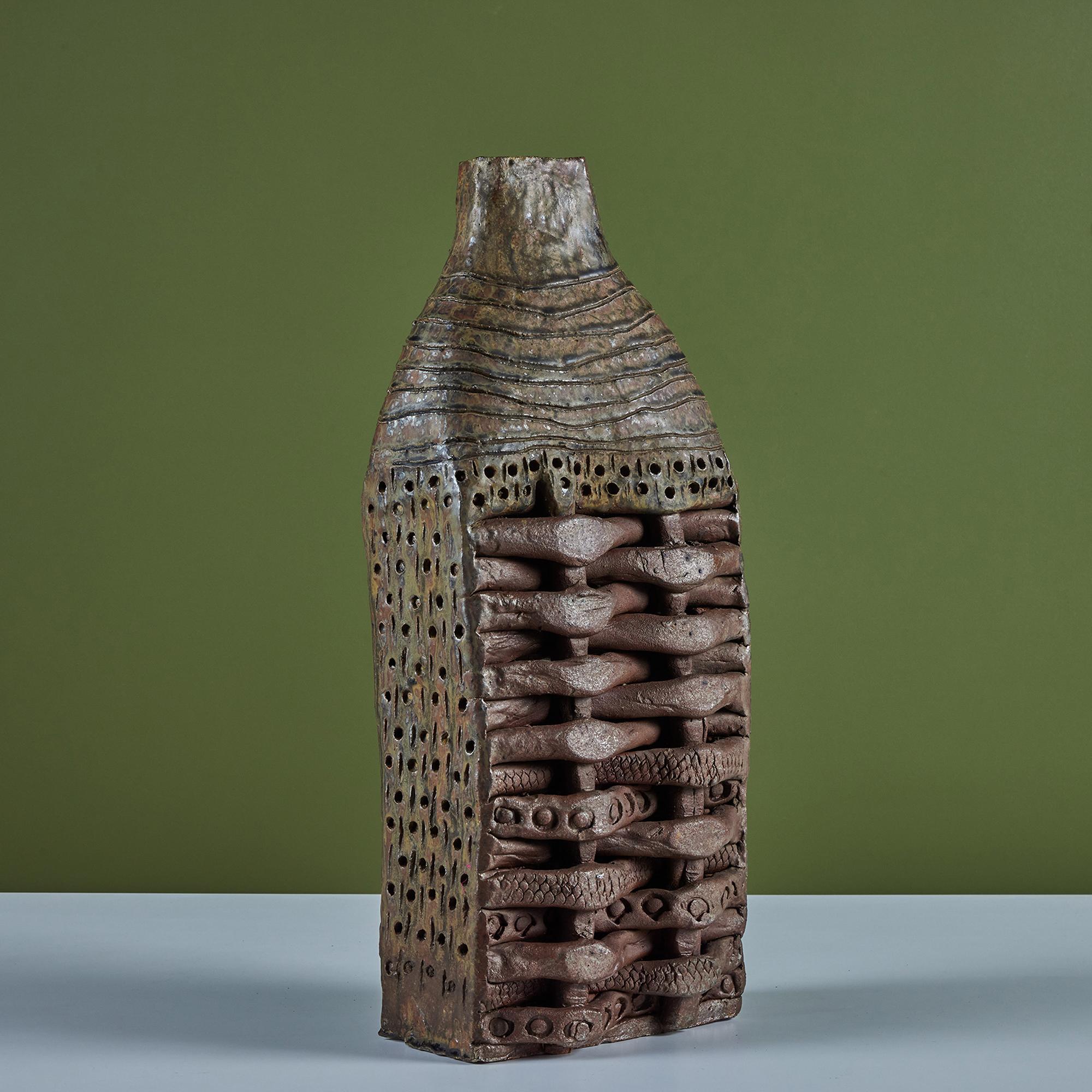 Ceramic sculpture by Japanese American artist, Takao Tomono. The sculpture features a woven vase like shape with incised geometric detailing. Tomono was born in 1935 and created many of his pieces through the 1960's.  Note this piece can not hold