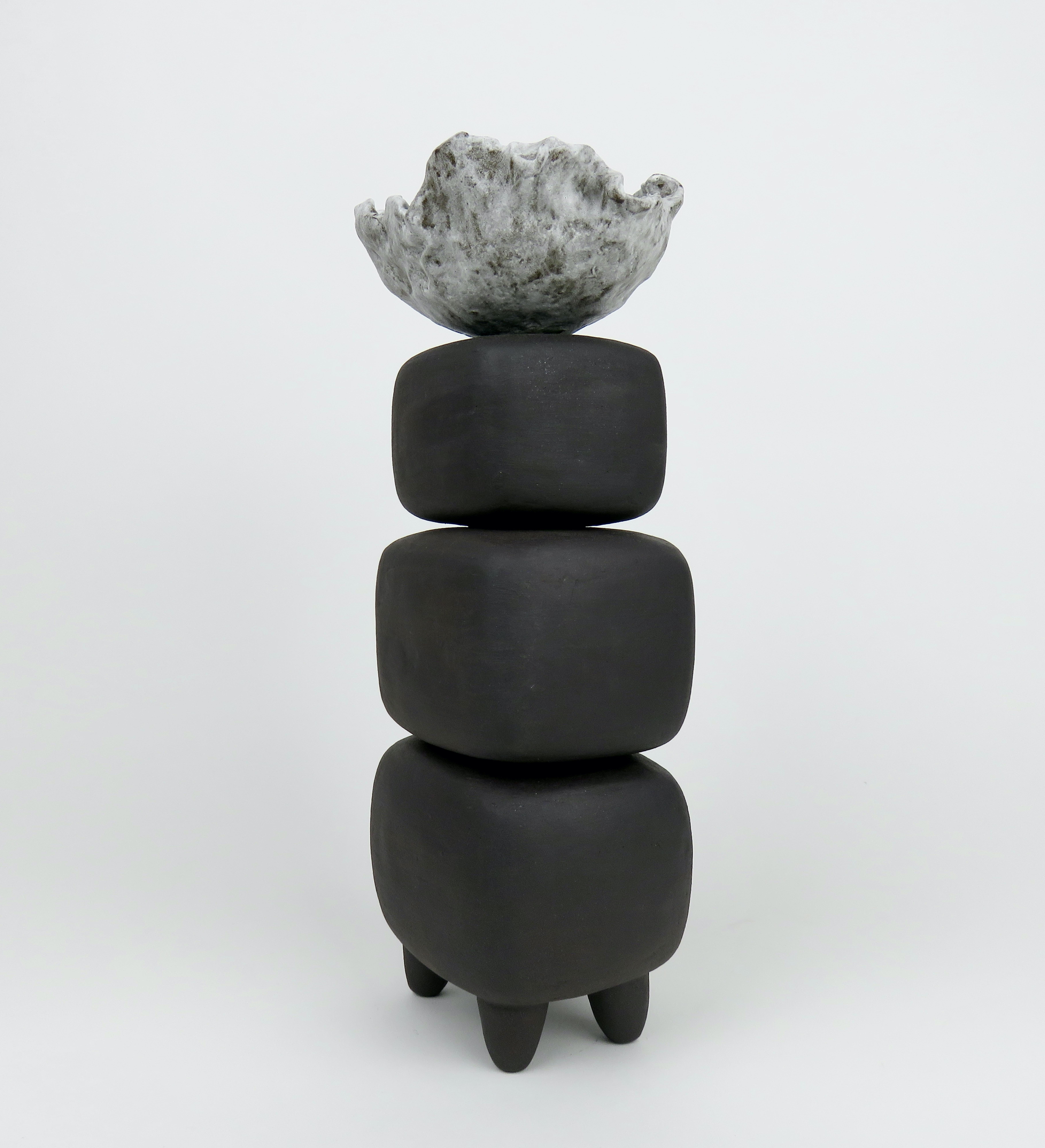 This hand built ceramic sculpture made of dark brown clay consists of three soft rectangular forms stacked on 4 distinct feet. It is topped with an organic, crimped bowl-like form in off-white glaze. The brown cubes are hollow and coated with a deep