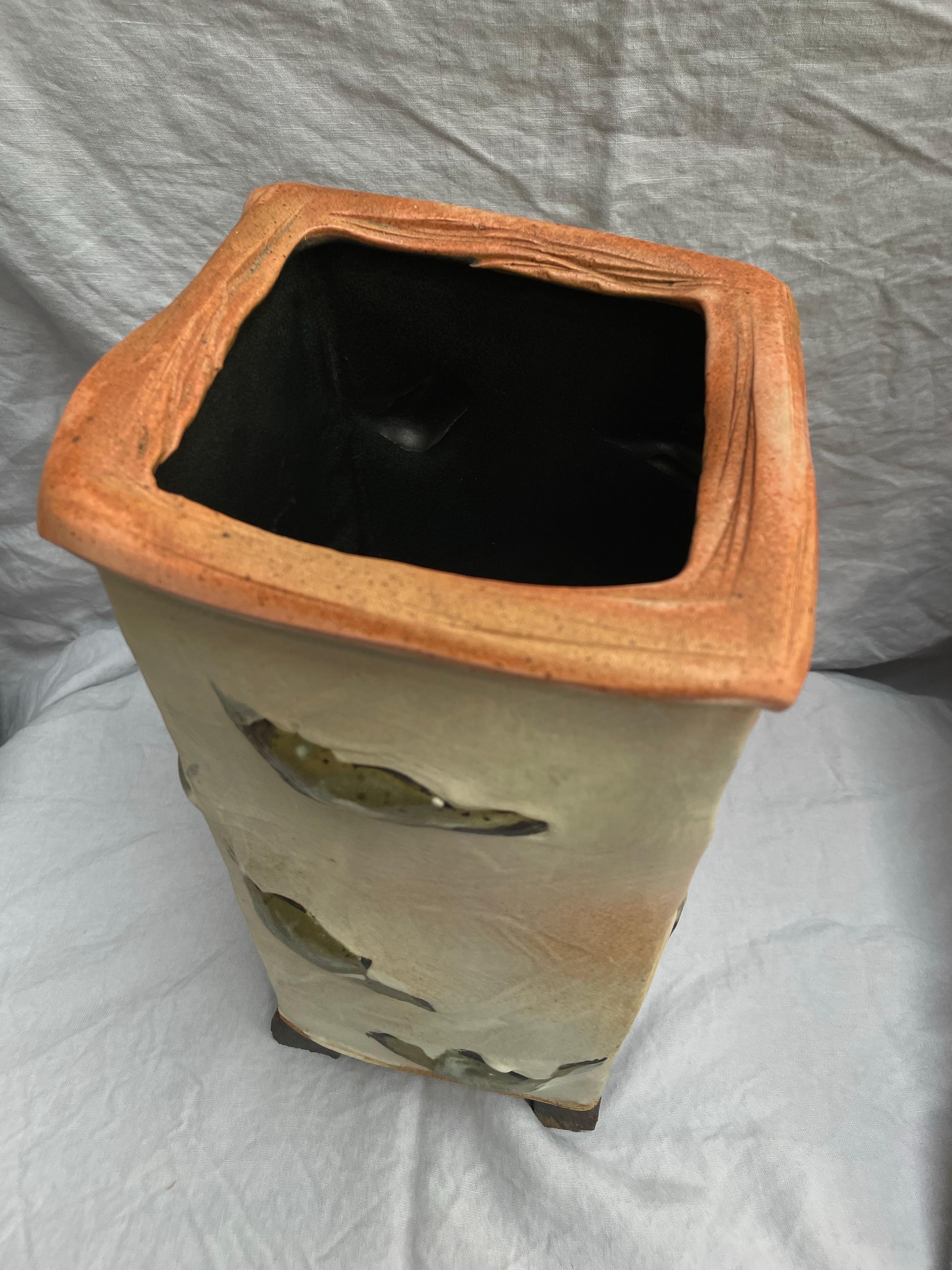 Eine auffällige, handgefertigte Keramikvase von einem Studio-Töpfer aus Nord-Michigan, die eine kühne, skulpturale Form und organische Oberflächentexturen aufweist. Das hohe, subtil verjüngte Gefäß hat ein bewusst unregelmäßiges quadratisches Profil