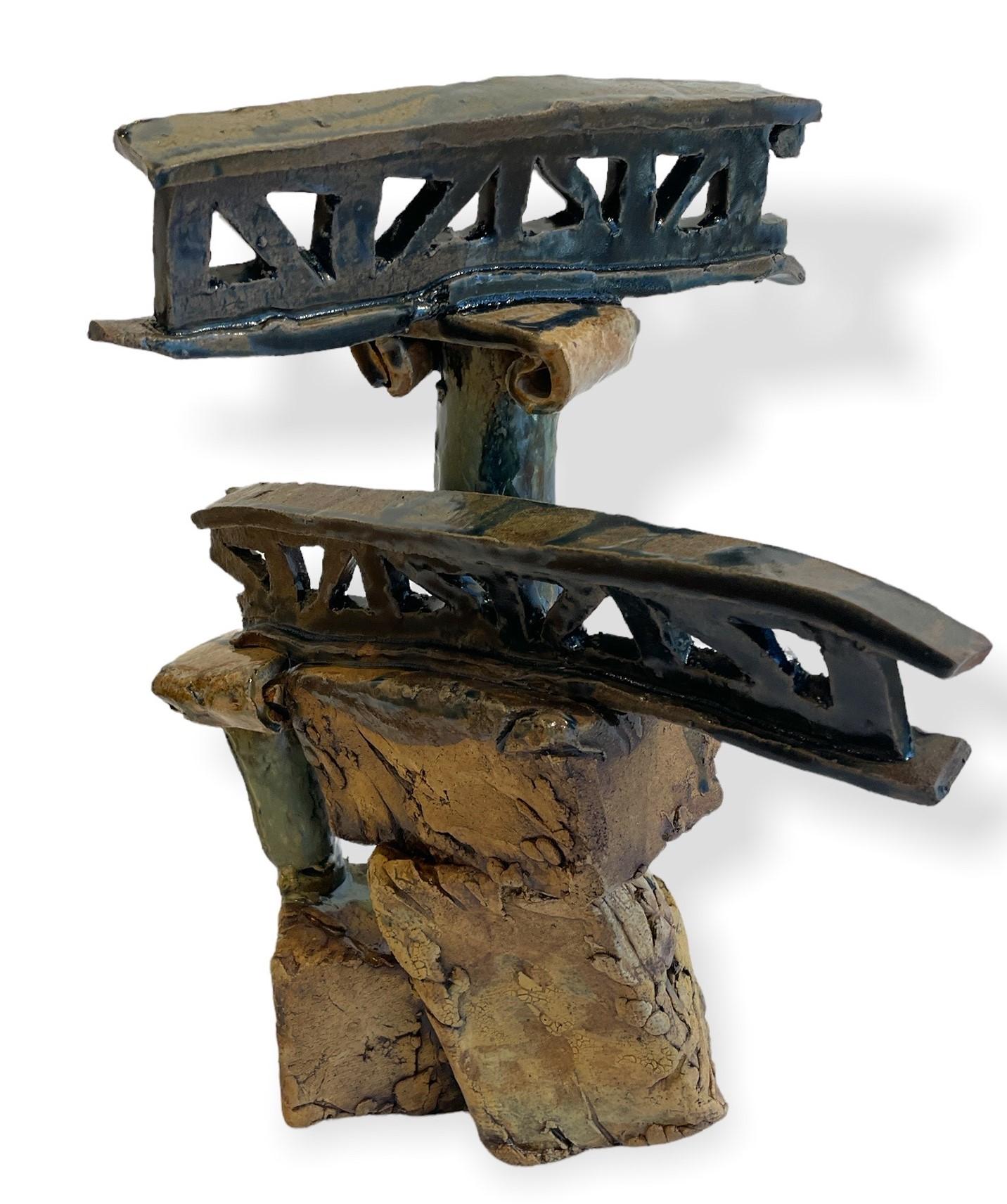 Bridge girders are suspended precariously atop Ionic columns in this chunky, hand built sculpture. Its earthenware coloring is complemented by the green, grey and blue drip glazes.

Steve Banks
Sculpture (Bridge)
stoneware, glaze
Measures: 14H