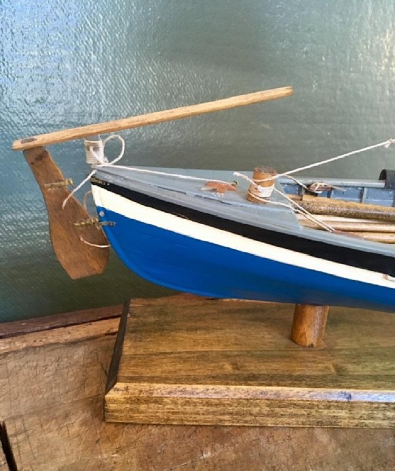 Vintage hand built model of a fully rigged 1860s New Bedford whale boat, crafted mid-20th century, having a carvel plank on frame construction, lateen sail stepped and raised, oars ready at hand, fully fitted with harpoons, lance, line tubs and