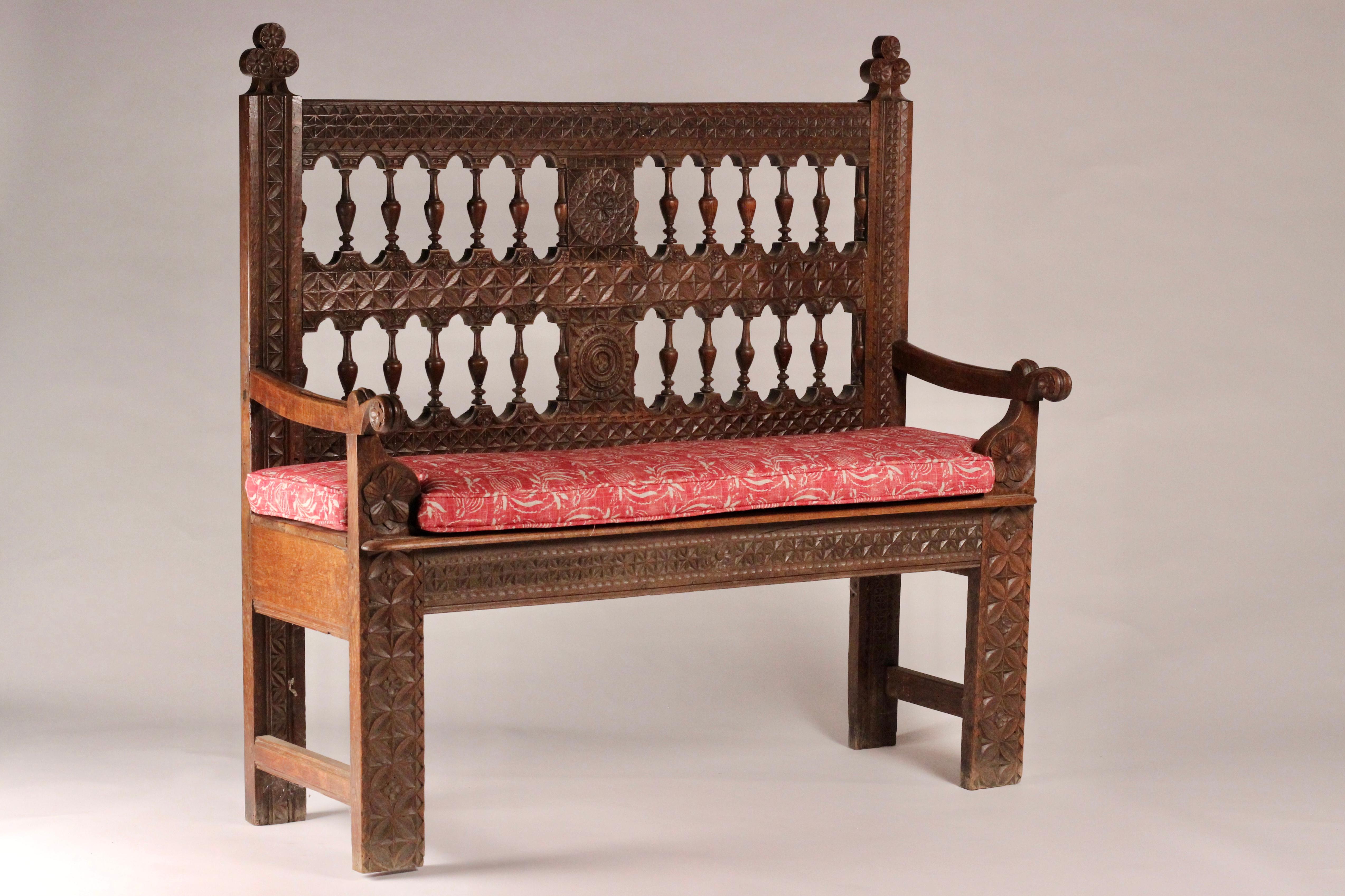 A hand carved and crafted oak 19th century French Gothic Revival bench or settle with an upholstered cushion or pillow. 

Ornately and intricately carved, displaying many of the typical motifs of the time of panels of Rosettes, flowers and foliage.