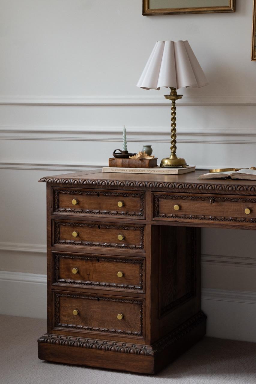 A remarkable antique pedestal desk from the mid-to-late 19th century, crafted with solid wood throughout and featuring exceptional hand-carved mouldings. The design embodies the elegance of a traditional English pedestal desk, enriched with Gothic