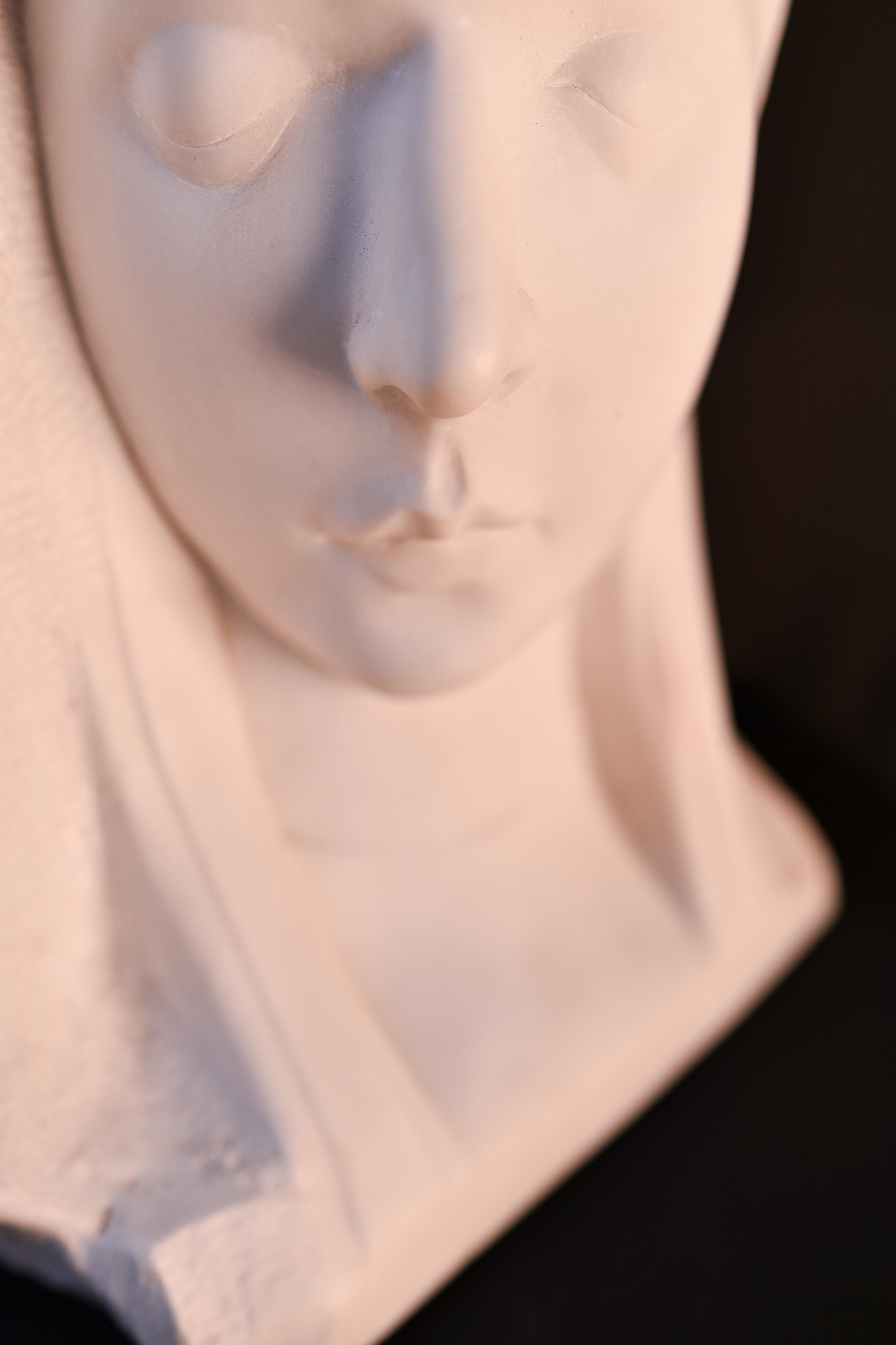 The bust portrays a woman with very serene and soft features, even with mystic appearance. 

The piece is signed, as can be seen on 1 of the pictures. 