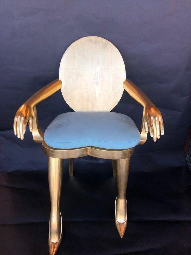 22-karat gold leaf. Hand carved wood armchair. The arms have carved hands and pointed toe heels at the feet.
Designed by Marjorie Skouras.