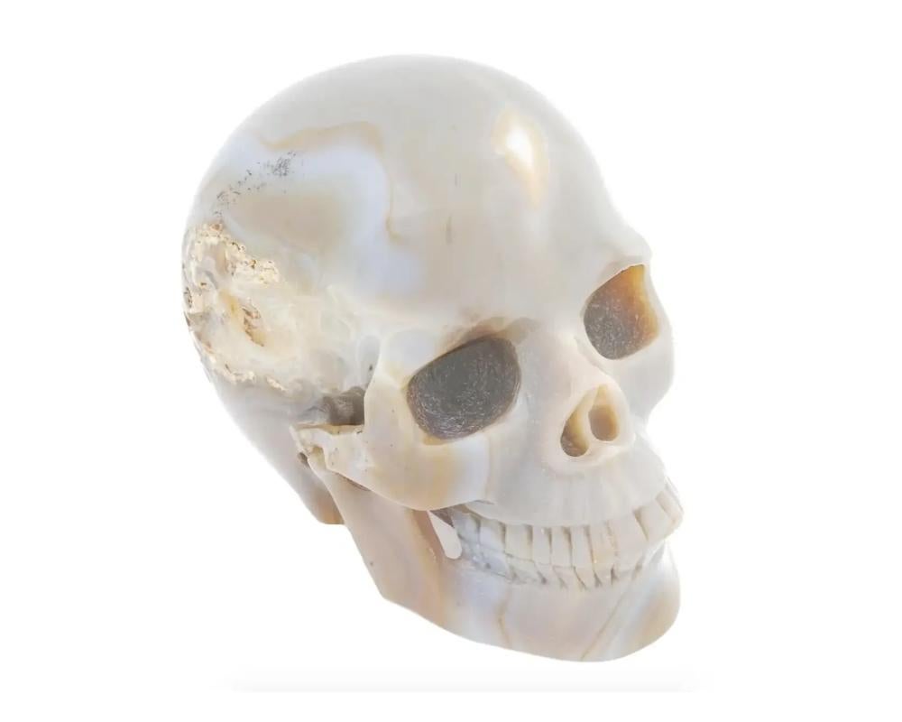 A natural agate carving representing a finely detailed human skull featuring a beautifully polished surface. Natural Gemstone Carvings, Desktop Accessories And Figurines For Home Decor.

Dimensions: H 4 1/4 in. All measurements are