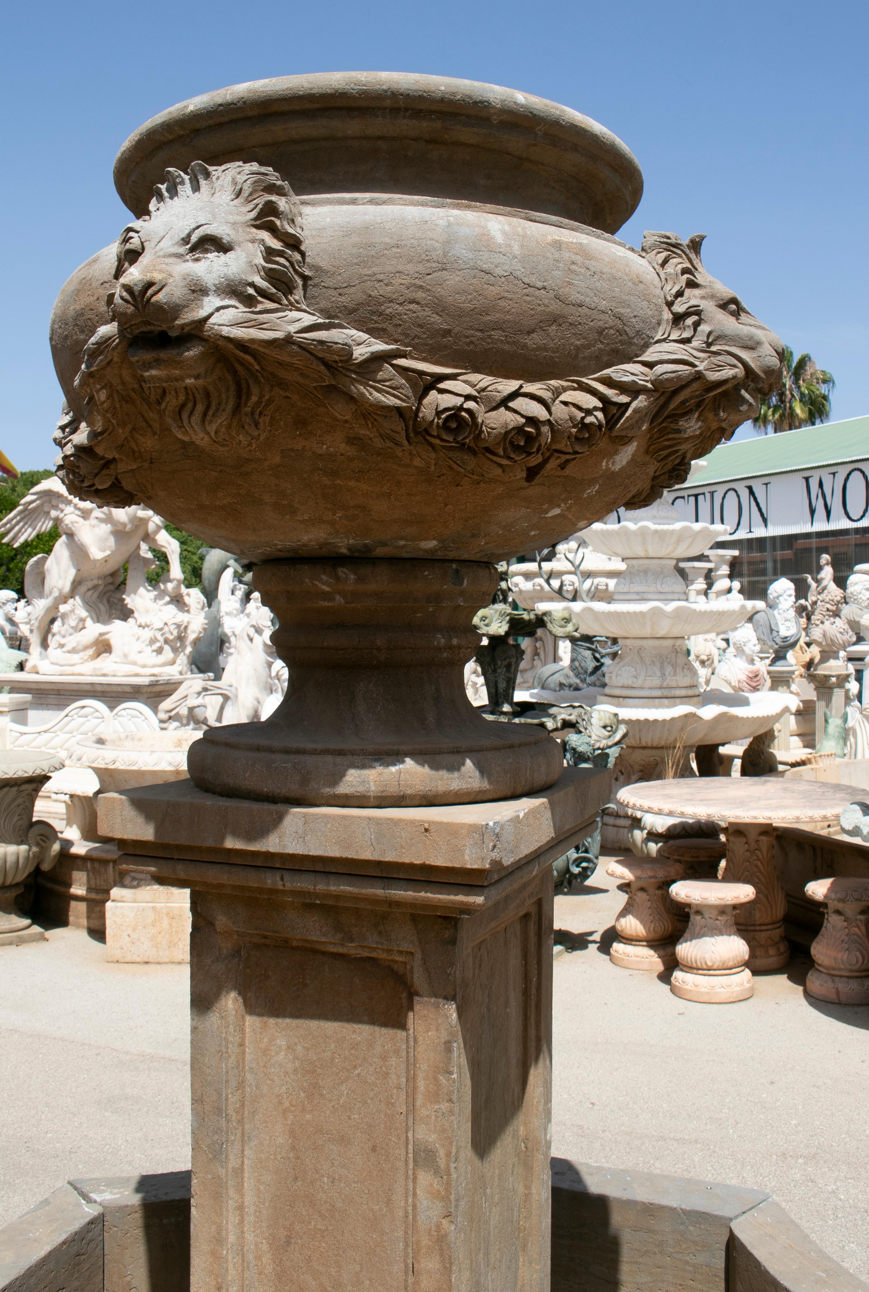 Hand carved aged marble fountain with pool, topped with ornamental planter urn decorated with lion heads and flower garlands.