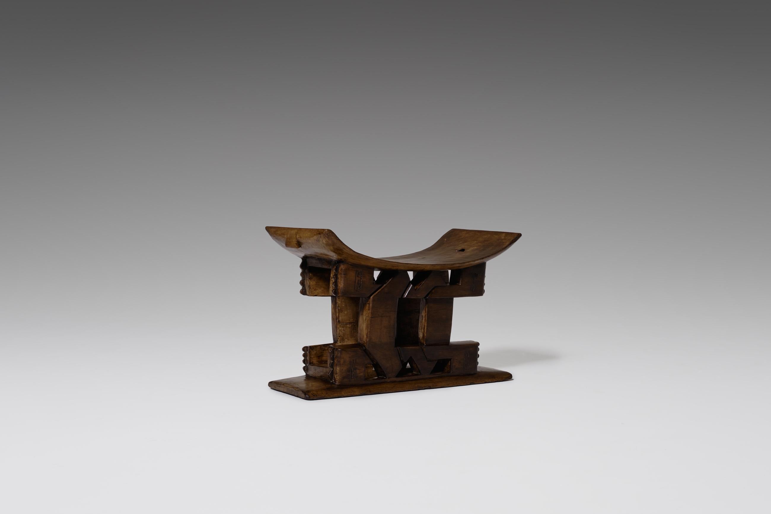 Original hand carved African tribal Ashanti stool, Ghana, early 20th century. Very nice almost graphic design carved out of one solid piece of wood. The curved seat is supported by a decorative center column which rises out of the flat bottom part.