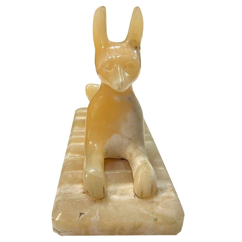 Scultura di Anubi (il dio egiziano con la testa di sciacallo) scolpita a mano in marmo alabastro. La statua è ispirata alla Grande Sfinge di Giza e presenta il corpo di un animale su una piattaforma.

Anubi supervisionava la mummificazione e guidava