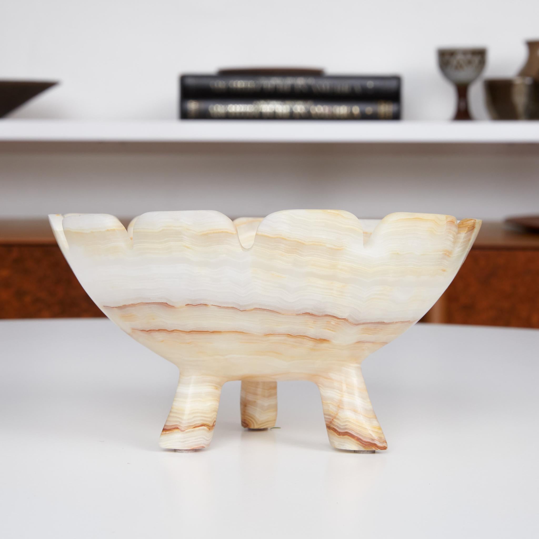 Hand carved alabaster bowl. This bowl is carved from a beautiful cream colored stone, accented with earthy brown, tan and orange veining. Carved from one piece, the tapered legs are part of the bowl creating a special seamless object. The wide top