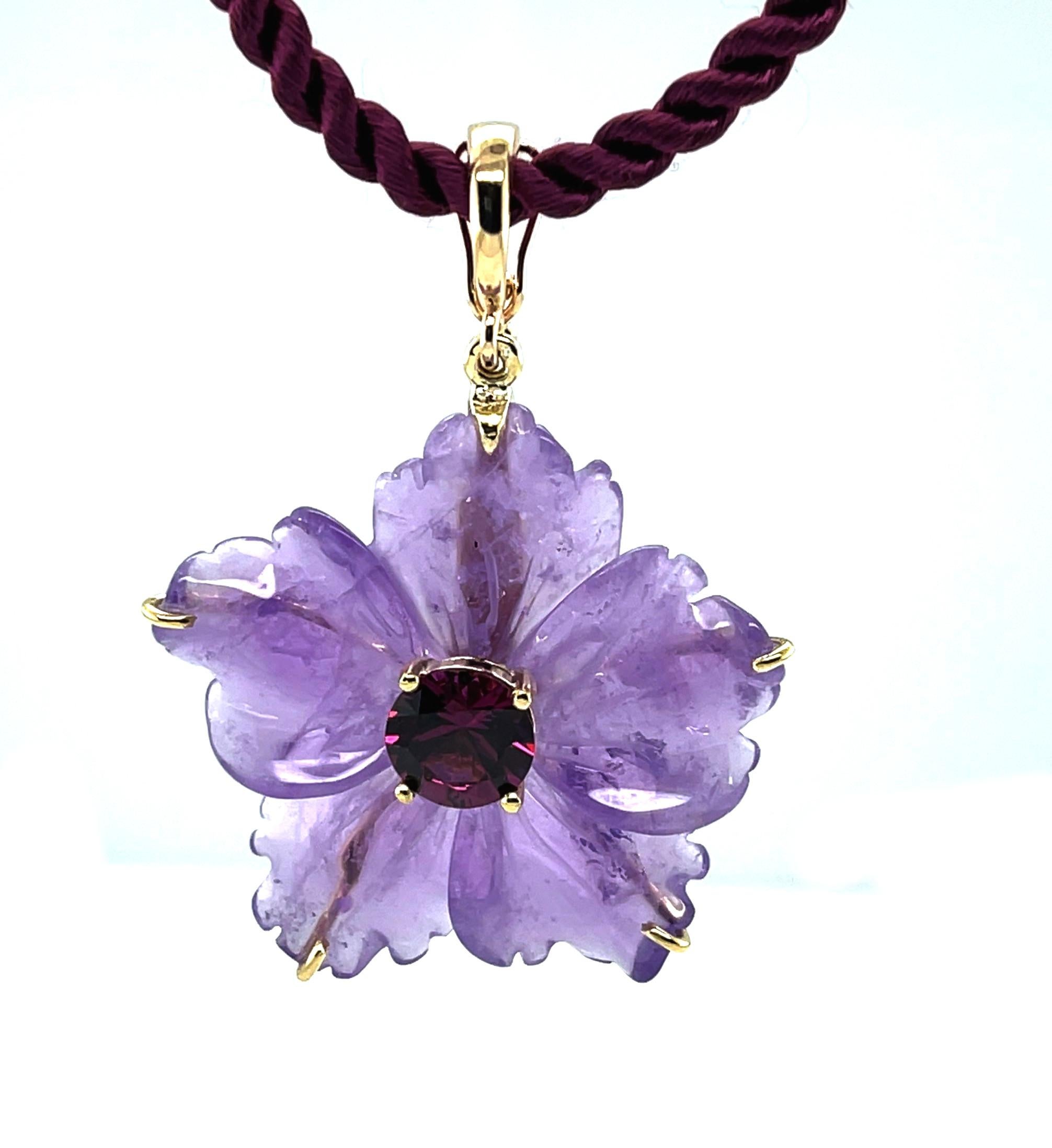 This beautifully carved amethyst flower pendant is so pretty and fun! A single amethyst crystal has been hand carved into a five petaled flower with lovely 3 dimensional curves and a soft, detailed outline. Set in the middle of the flower is a