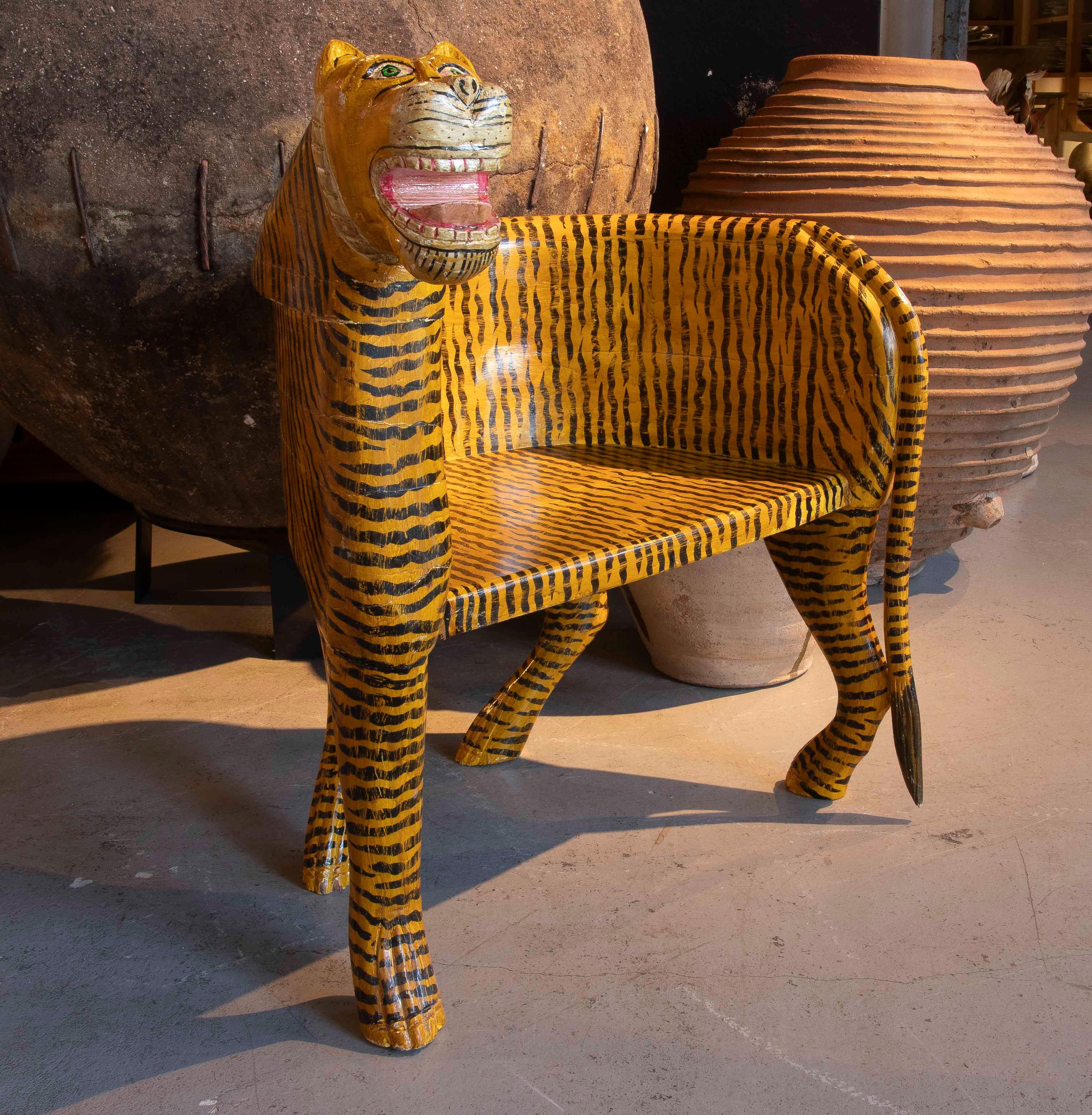Einzigartige handgeschnitzte und handbemalte Skulpturenbank in Form eines Tigers. Dieses aus Holz gefertigte Stück verbindet Funktionalität und dekorative Kunst mit einem Design, das sich durch seinen verspielten und ausdrucksstarken Charakter