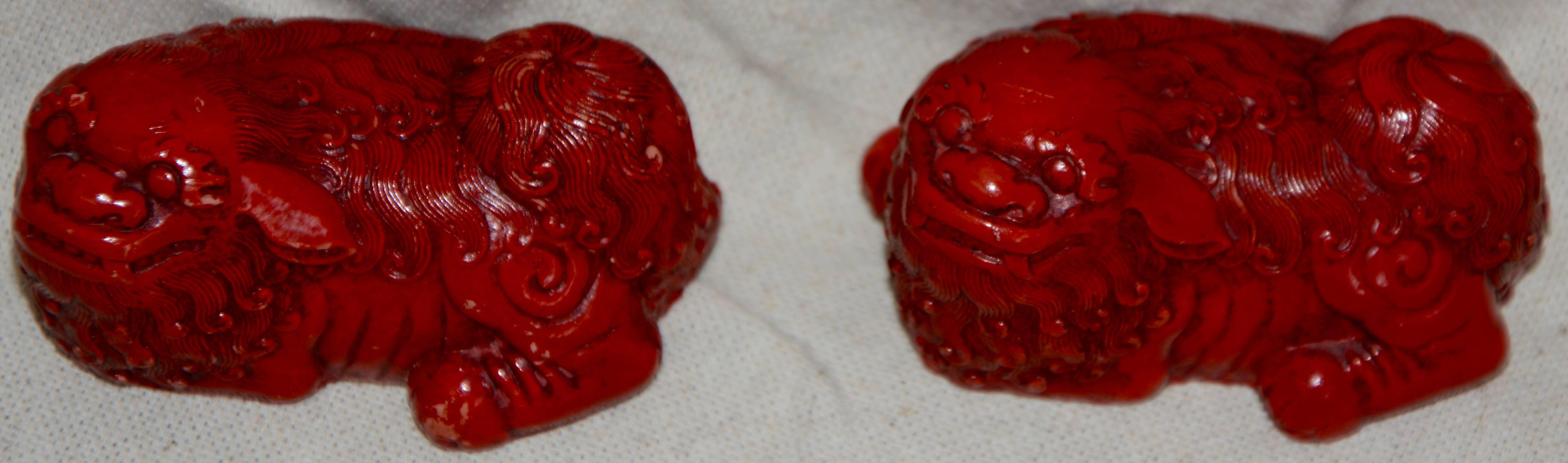 This pair of small Asian Foo Dogs have been creatively hand-carved and tinted a lovely cinnabar color. The carved details are highlighted in a dark tint. The work on these collectible pieces is exquisite.