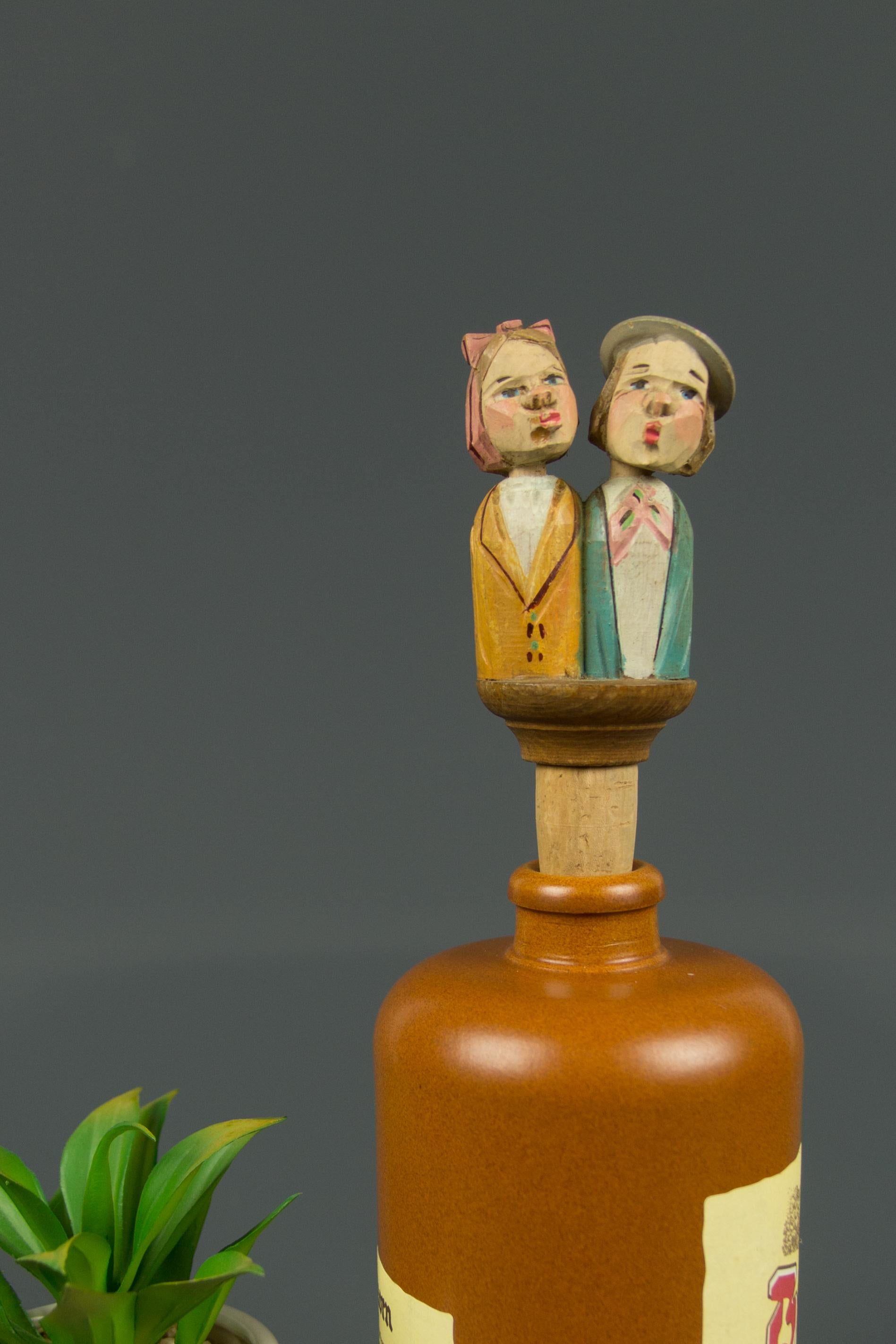 Adorable hand carved and hand painted mechanical bottle stopper. It depicts a lovely couple from the 1950s. There is a wooden lever on the back of the couple and when it is pulled down, the couple raises their heads and turns towards each other to