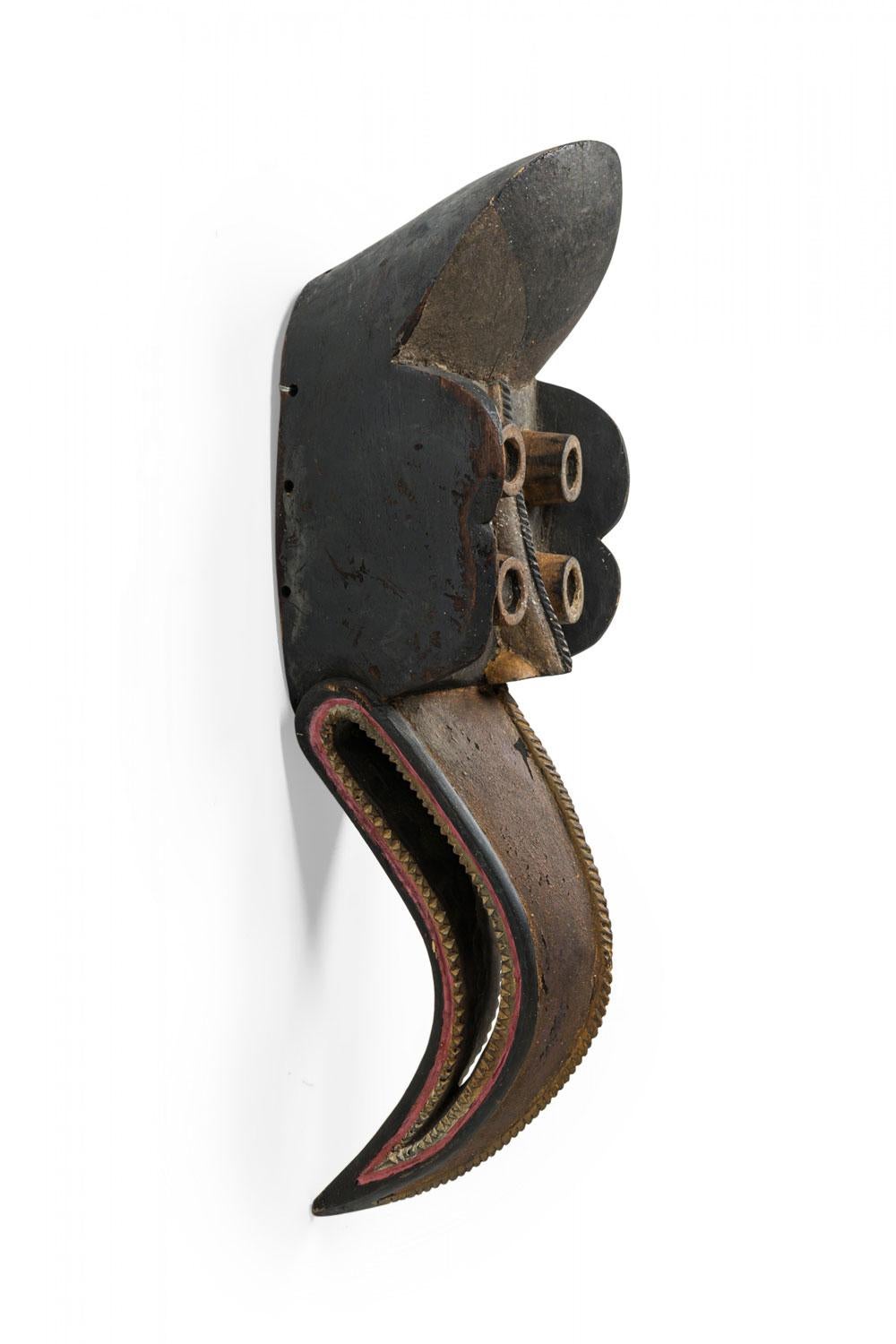 Asikanischer Stil Geschnitzte und bemalte Holzmaske in Form eines Vogels mit 2 Paar zylindrischen Augen und einem durchbrochenen, schrägen, gezackten Schnabel.

Abnutzungserscheinungen durch Alter und Gebrauch. Einige Verluste, Verfärbungen,