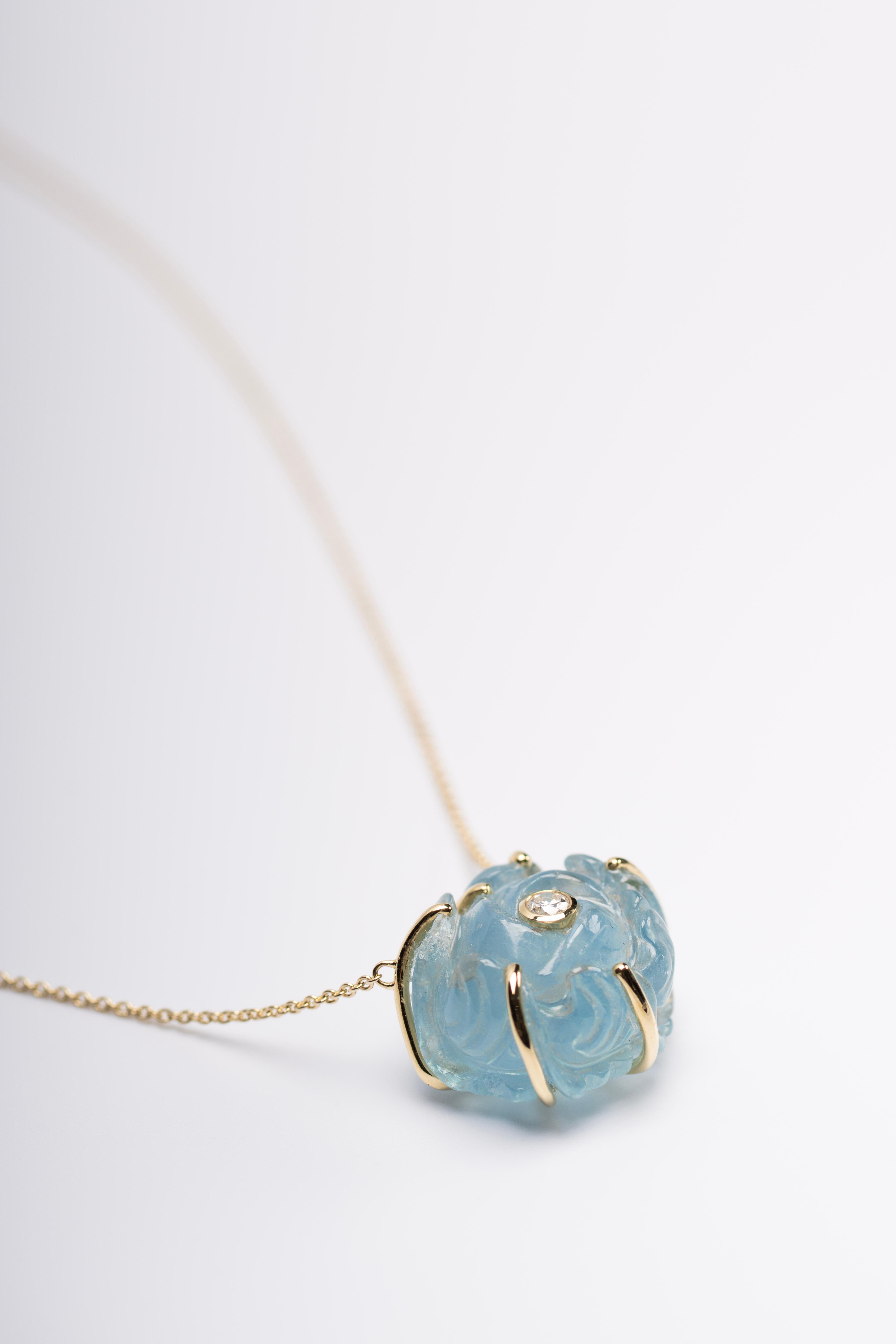 Le pendentif Rosaline présente la même beauté éthérée que les boucles d'oreilles, avec une rose d'aigue-marine sculptée à la main dans un doux bleu alpin, entourée d'un diamant brillant, et suspendue à une délicate chaîne en or 18 carats. La pièce