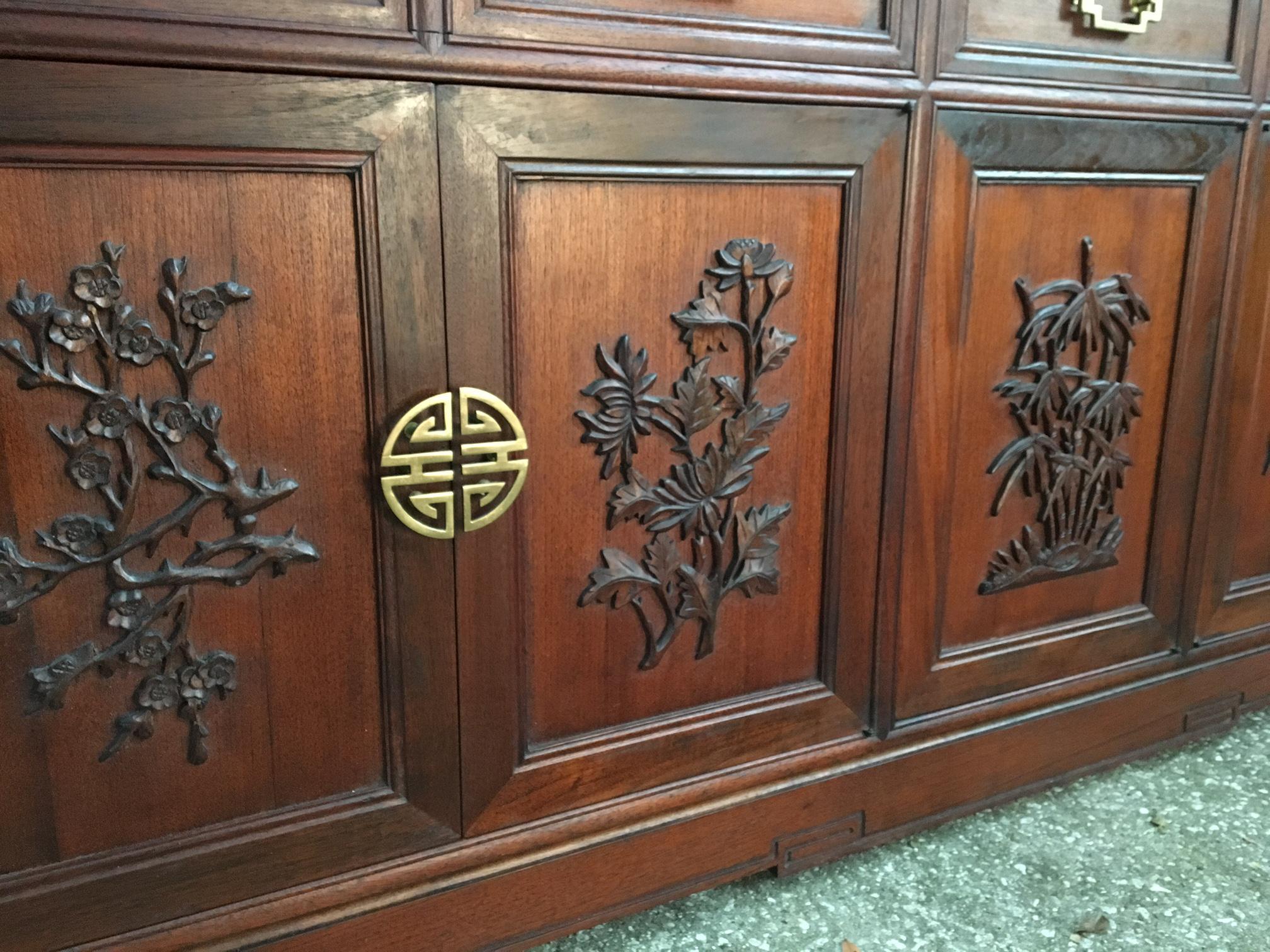 Your Hollywood Regency dining room will be complete with this Chinese chinoiserie display cabinet by Ricardo Lynn. Features detailed carvings of palm, bamboo and other tropical trees. Stunning sculptural brass hardware. Excellent vintage condition