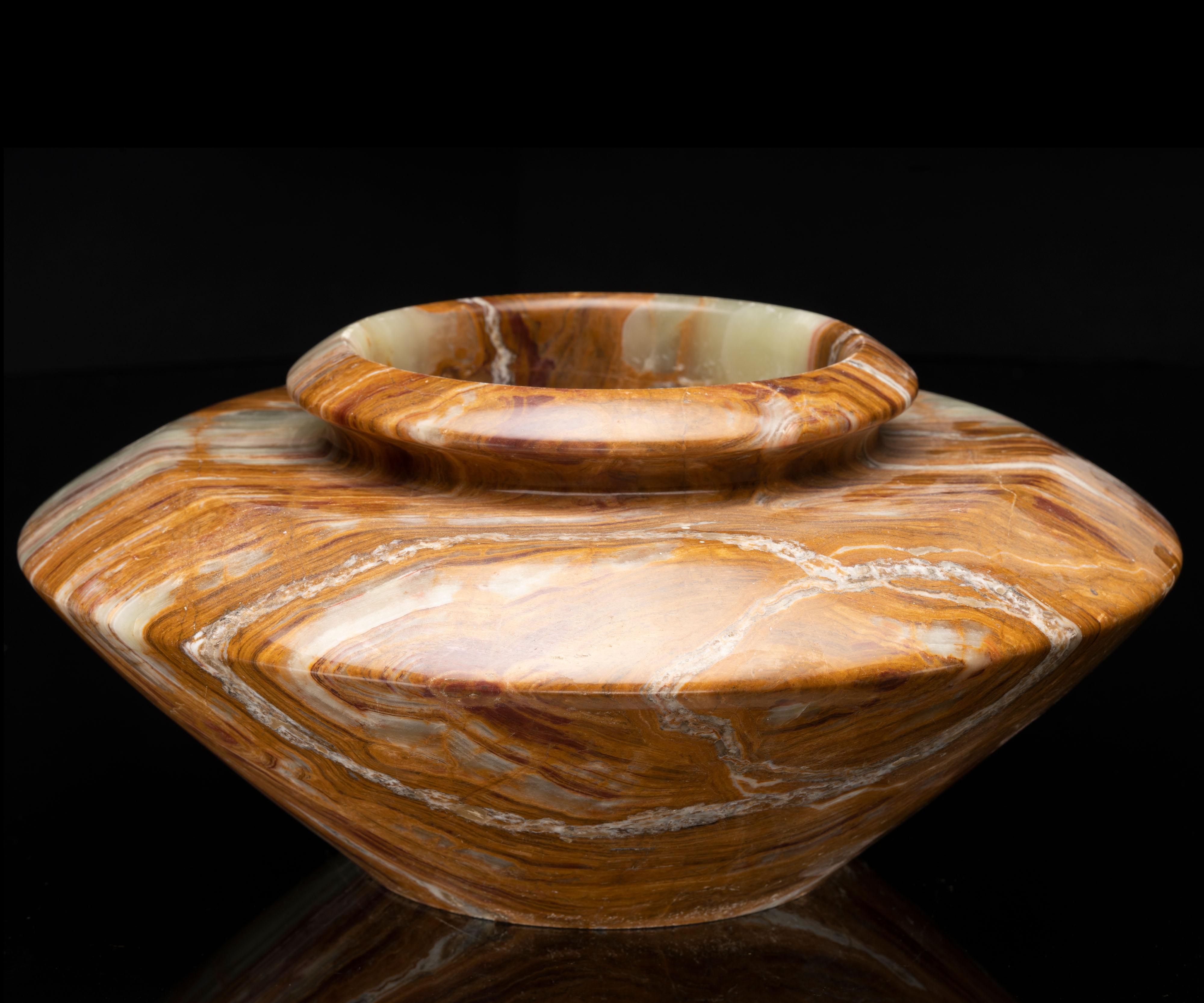 Ce magnifique pot de fleurs sculpté à la main est taillé dans un seul morceau d'onyx rubané de haute qualité provenant du Pakistan. Avec ses bandes et ses tourbillons d'un brun riche, d'un vert verdoyant et d'un beige, cette pièce de décoration AAA