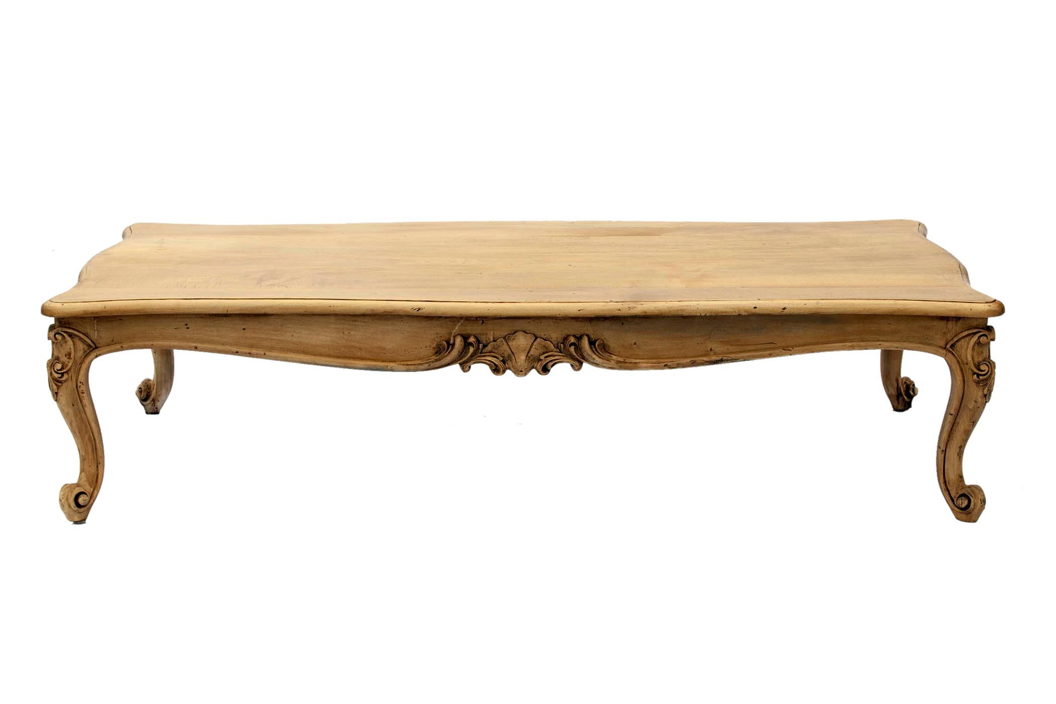 Hand carved European cocktail table in pale hardwood.
An elongated rectangular, the top features long planks resting on four provincial legs with a hand carved apron.
The oversized table features a natural wax finish over a clear French varnish.
The