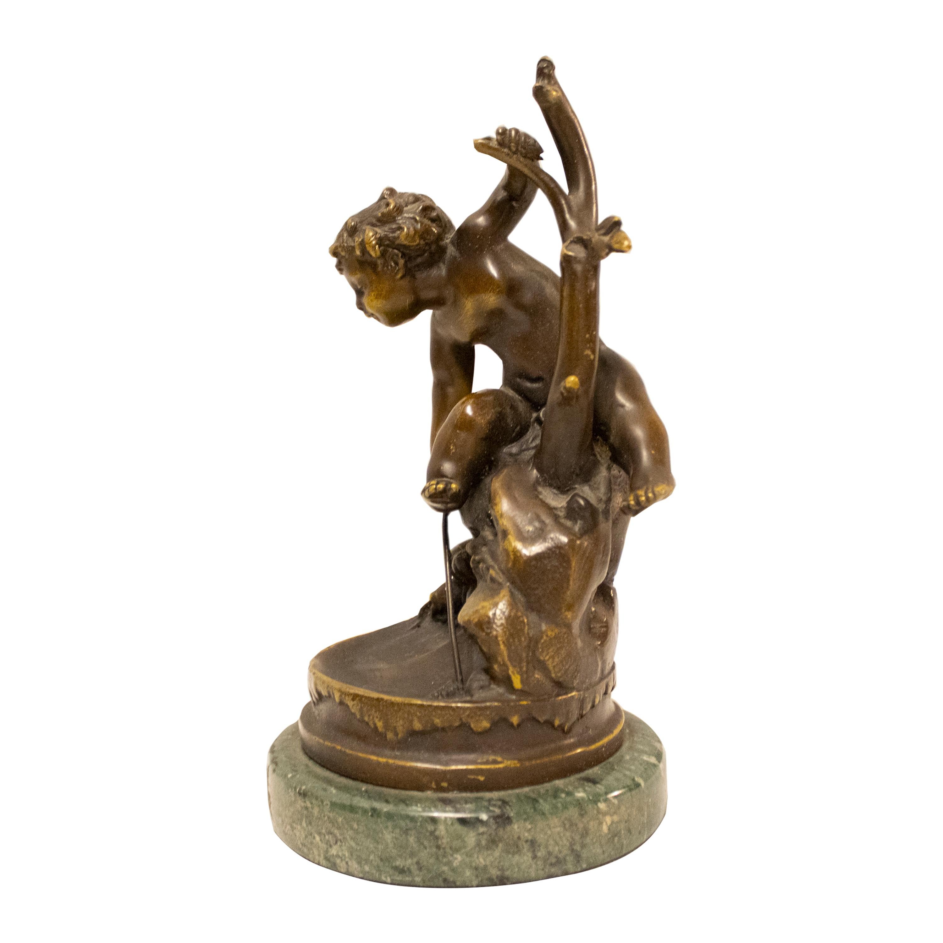 Scultura di un ragazzo che gioca, realizzata in bronzo massiccio intagliato a mano con patina nera e base circolare in marmo verde. Francia, XX secolo.