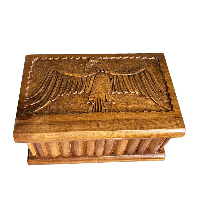 A large wooden hand-carved puzzle box with an eagle motif. This large box is created from wood and is rectangular in shape. This box is unique as it has a hidden compartment to hold a key to lock the box. (Key not included) To open the box, pieces