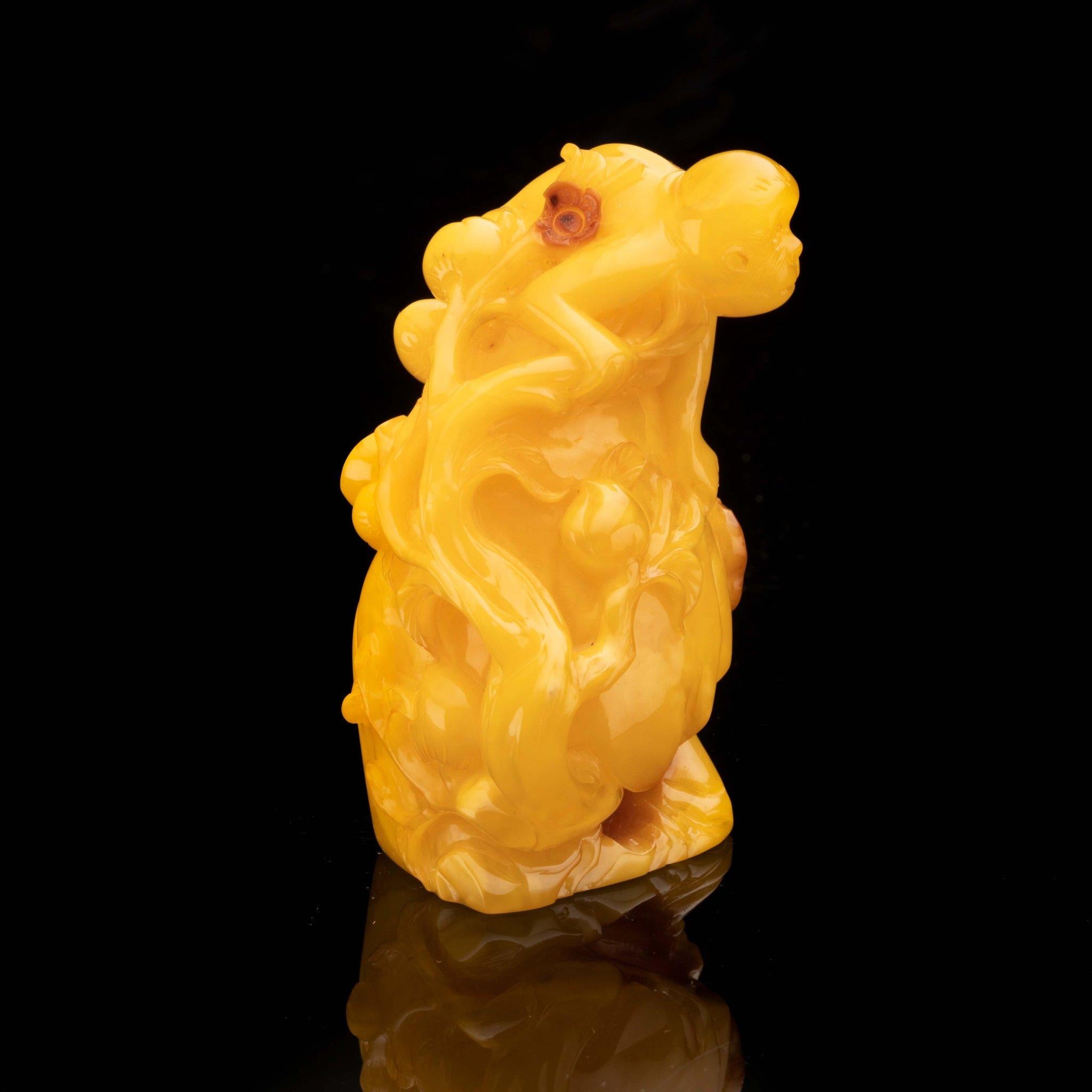This unique and stunning scene depicts a monkey perched on a rock, decorated with intricately realized vines and buds. This piece featuring exquisite detail is hand-carved from a single piece of excellent quality butterscotch amber from Ukraine and