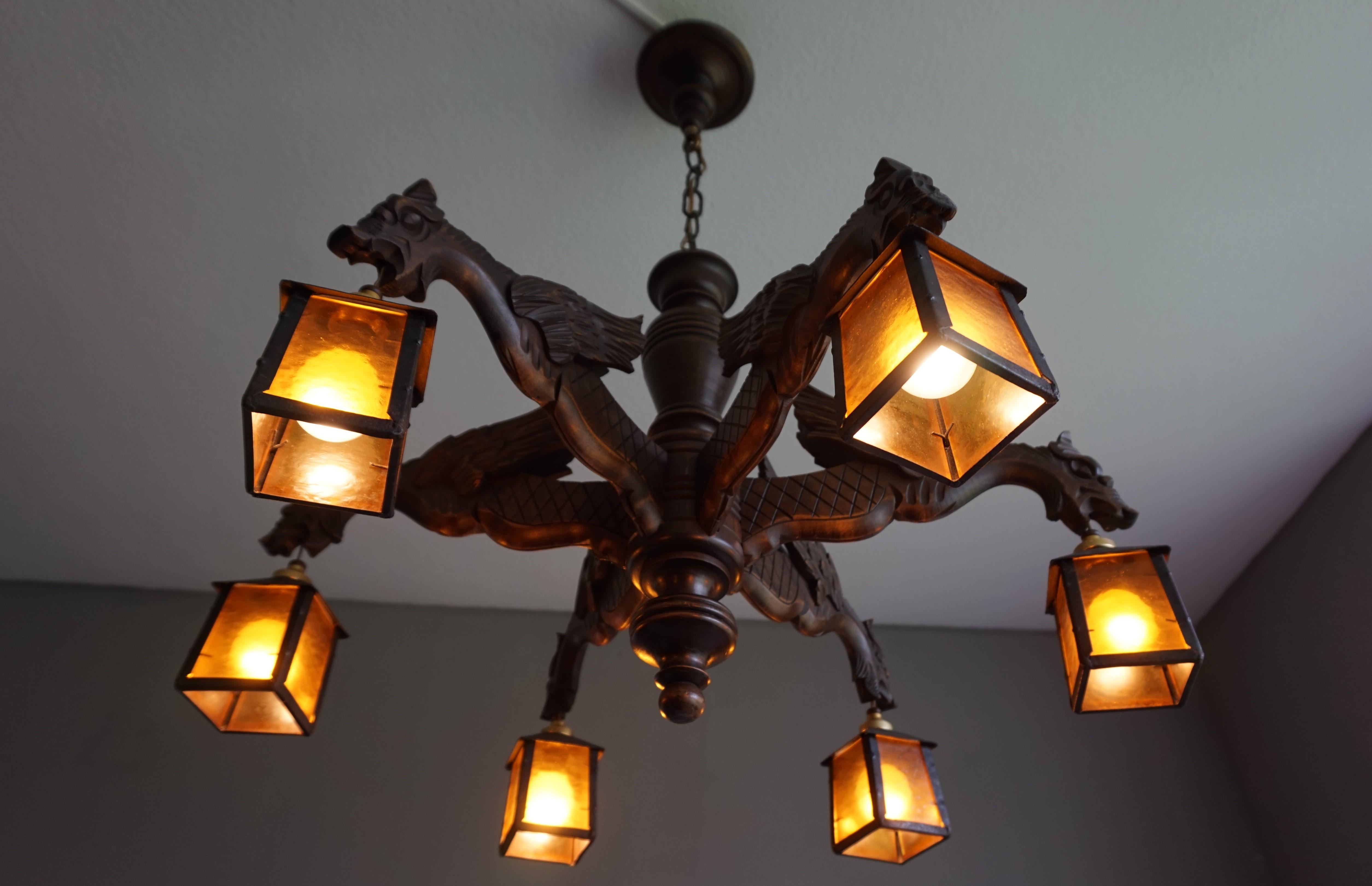 Antique wooden light fixture with dragons and hand forged, wrought iron lanterns.

This handcrafted, excellent condition chandelier comes with six stunning and well carved, winged dragon arms. Protruding like mediëval gargoyles on the ledge of a