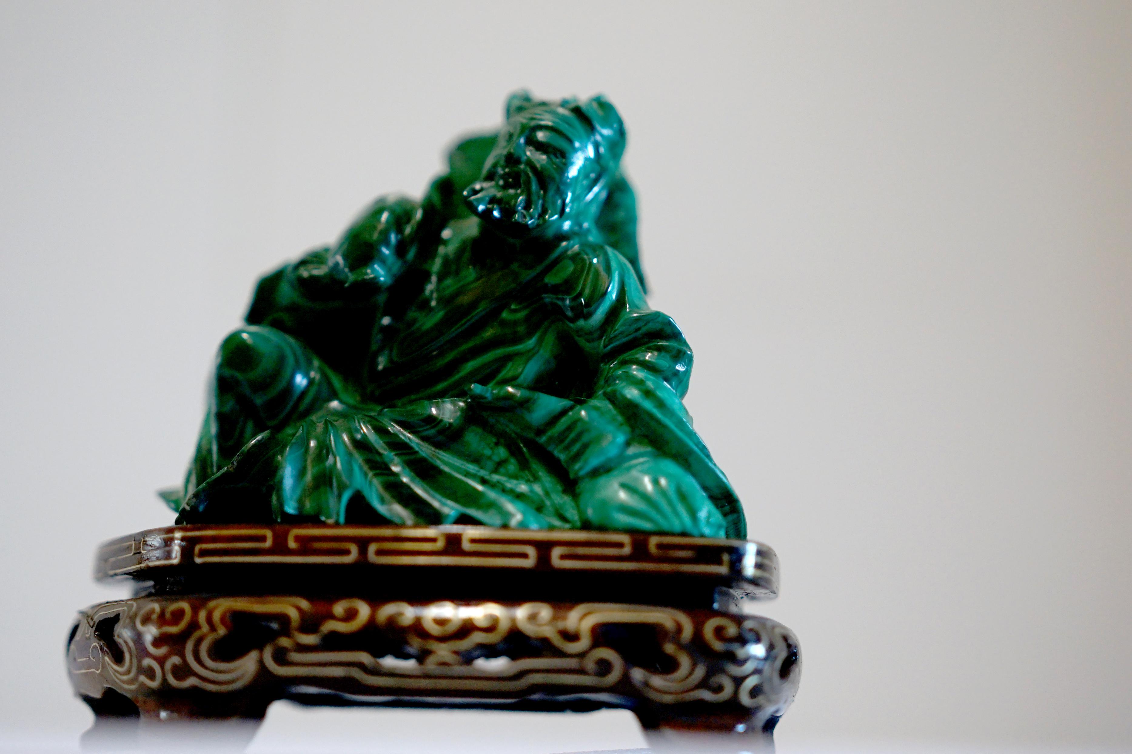 

Description:
This exquisite hand-carved Chinese malachite sculpture depicts a wise elder seated in flowing robes, rendered in rich striations of deep emerald green. The craftsmanship captures both movement and serenity, evoking traditional
