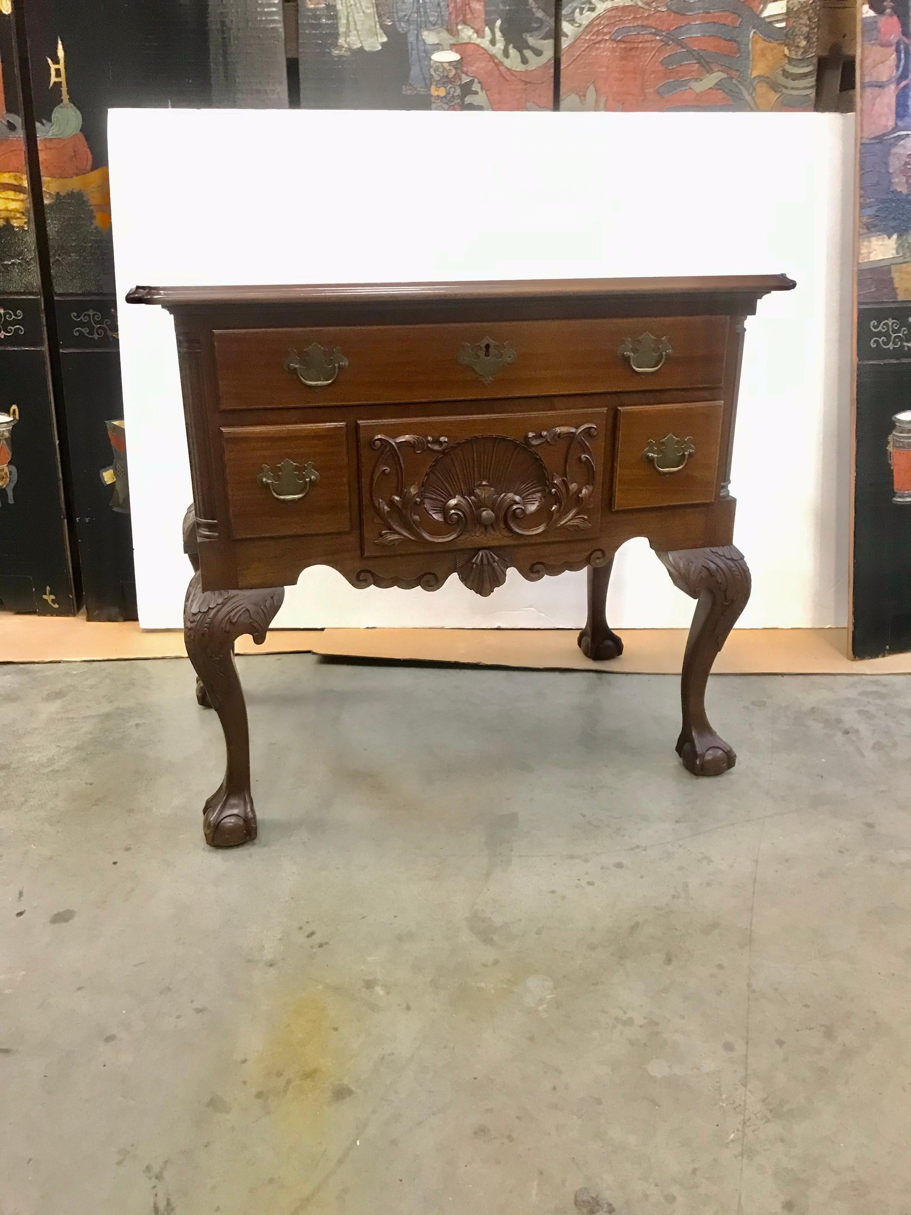 An early 20th century hand carved mahogany Philadelphia Chippendale style lowboy. The larger top drawer with three lower smaller drawers with shell carving in the center one. The legs beautifully carved with acanthus leaves resting on classic ball