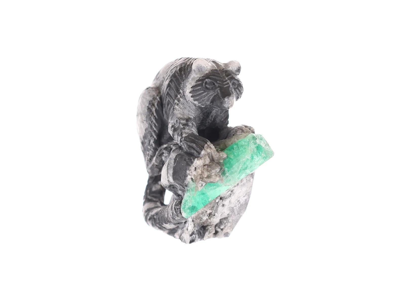 This beautiful and one-of-a-kind rough Colombian emerald sculpture. Featuring the one and only red panda; hand-carved with intricate detail along its coat and tail made of black and gray shale. The panda sits over a cliff with a natural Colombian