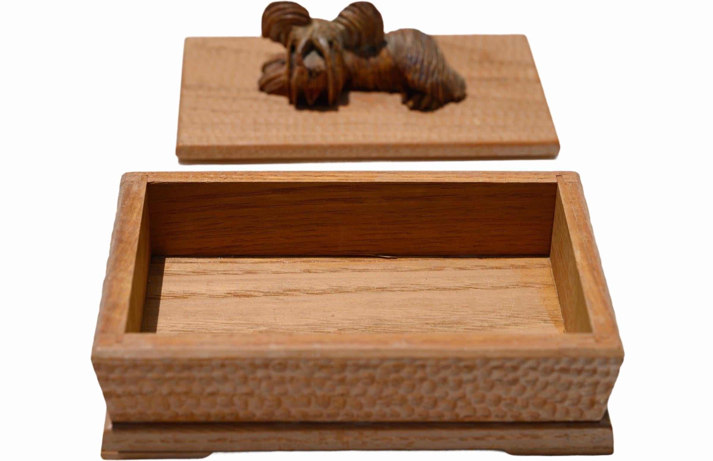 A beautifully hand carved wooden keepsake box with an adorable sculpted dog on top of the lid. 
The exterior of the box is stylistically carved with deep cuts and indentions in a repeating pattern.

Measures: 6 1/4