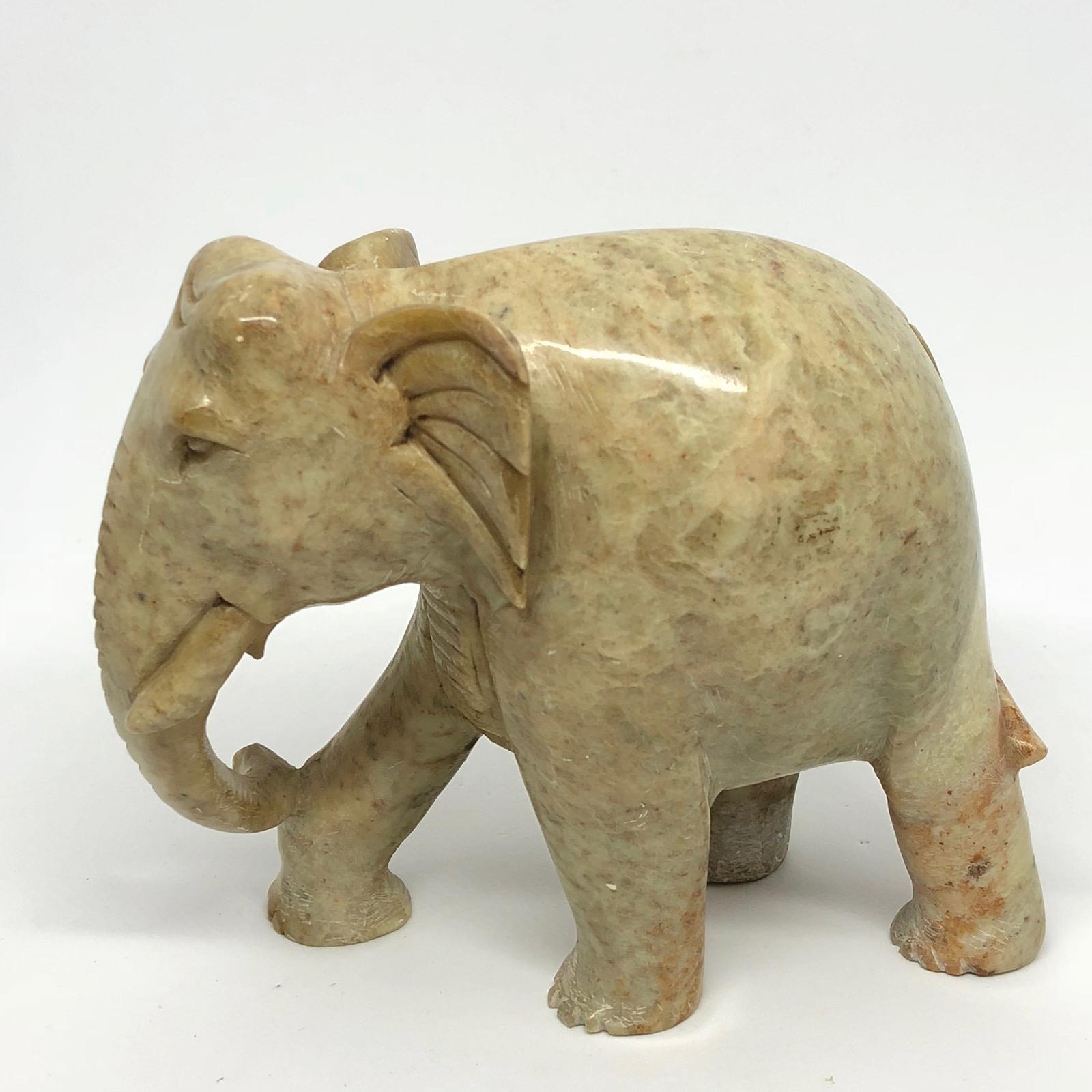 A decorative hand-carved elephant sculpture. Some wear but this is old-age. Made of a heavy stone, think its marble. We think it is from Asia and was made in the 1970s.