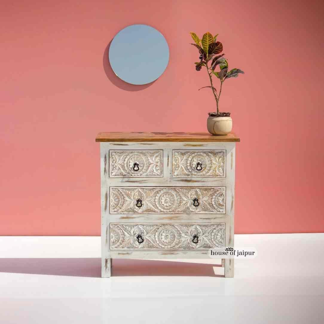 Cette superbe commode allie l'art de la sculpture à la main à un rangement pratique pour tous les jours. Avec sa finition blanche vieillie et son plateau en bois naturel, cette pièce présente des sculptures florales détaillées sur les quatre