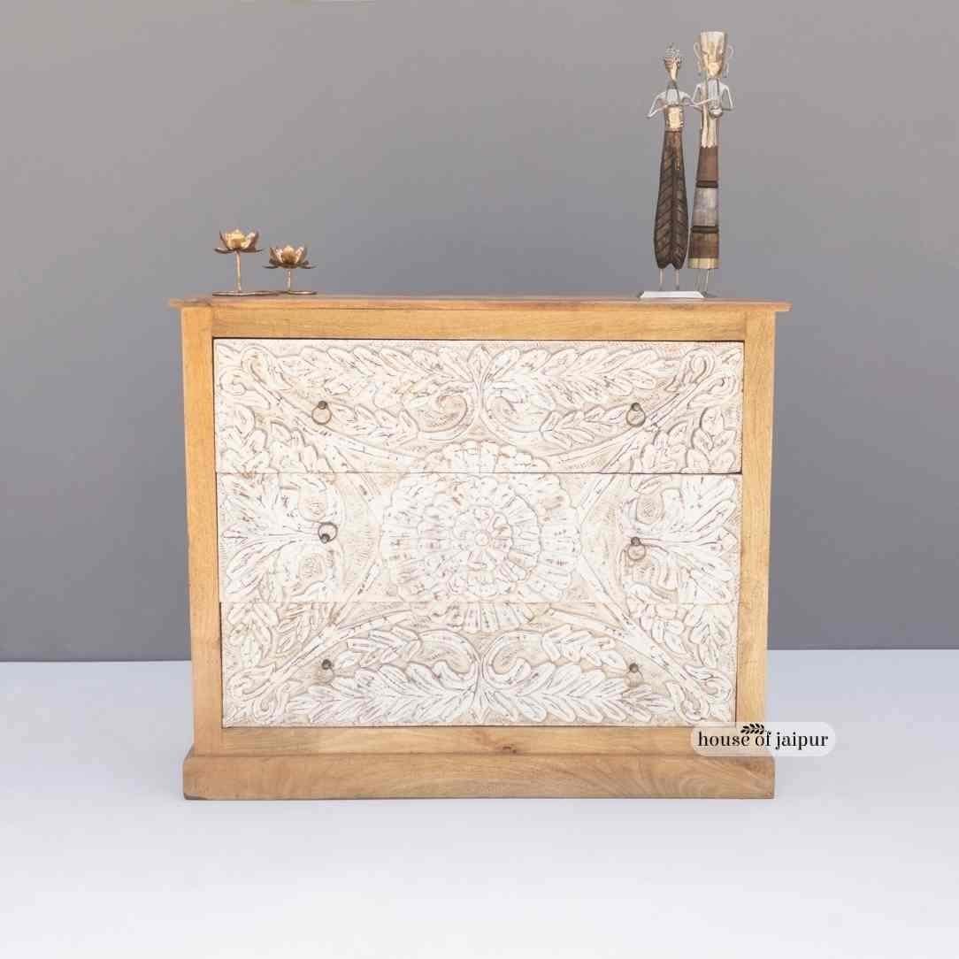 Cette commode, fabriquée à la main de manière exquise, allie l'art de la sculpture traditionnelle à la fonctionnalité moderne. La façade présente un motif floral et feuillu complexe, entièrement sculpté à la main et rehaussé d'une finition blanche
