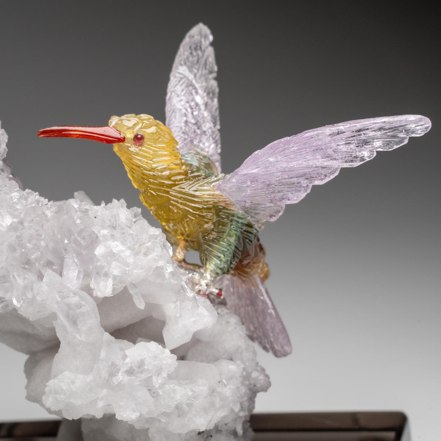 Esta talla de Colibrí es una obra de arte única, tallada en fluorita de calidad de museo, con ojos de granate y pico de cornalina. Los colibríes están posados sobre una flor de amatista y montados en un soporte a medida para exponerlos cómodamente.