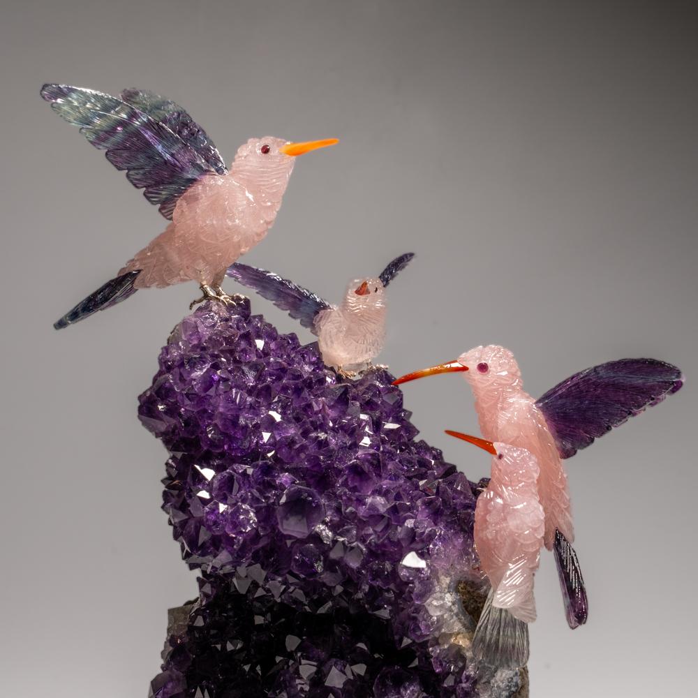 This Hummingbirds carving is a unique piece of art, carved from museum-quality fluorite with onyx eyes and a carnelian beak. The owls is perched atop a green tourmaline and quartz matrix and mounted on a custom stand for convenient display. This