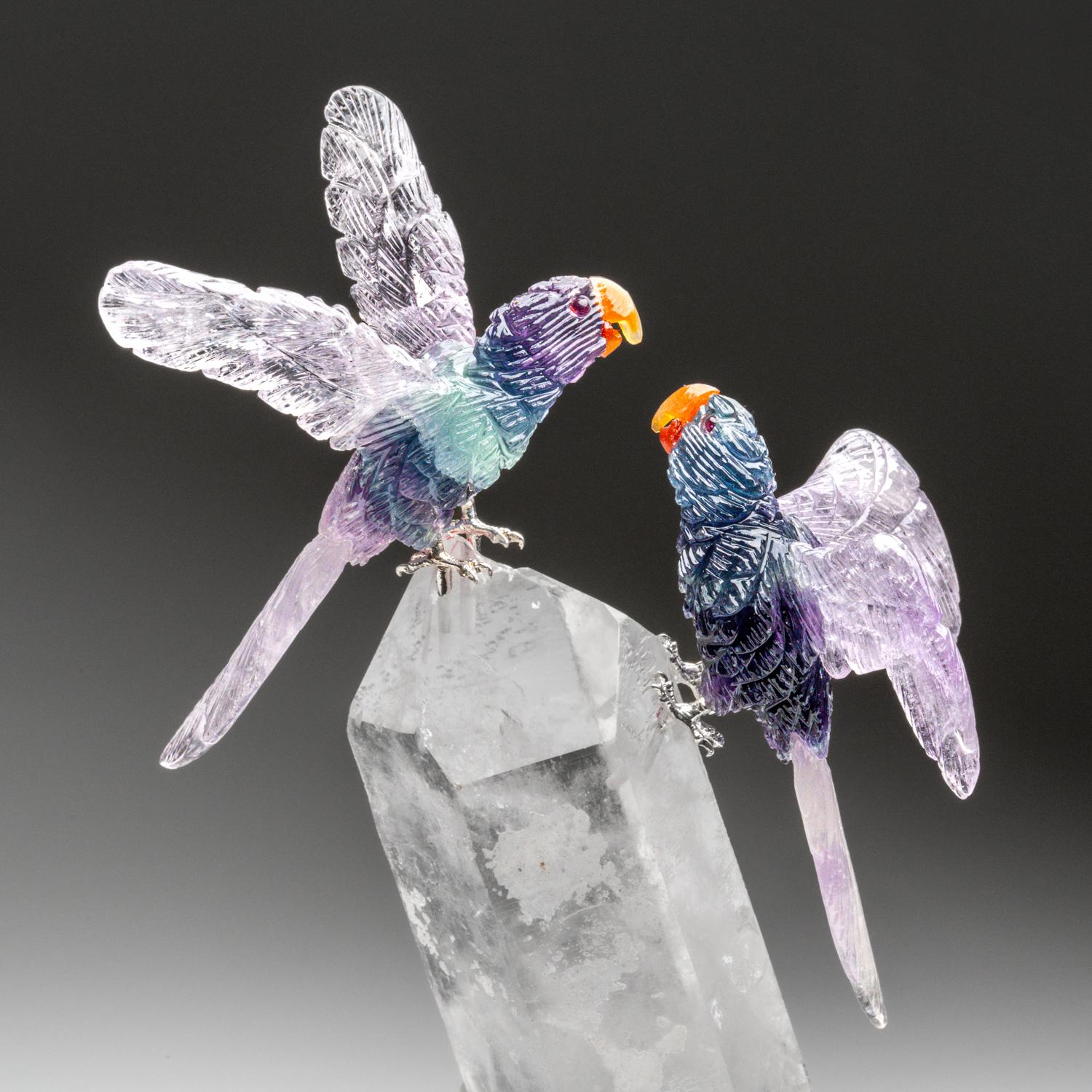 Cette sculpture de perroquet est une œuvre d'art unique, sculptée dans de la fluorine de qualité musée, avec des yeux en grenat et des becs en cornaline. Les perroquets sont perchés sur une pointe de quartz transparent et montés sur un support