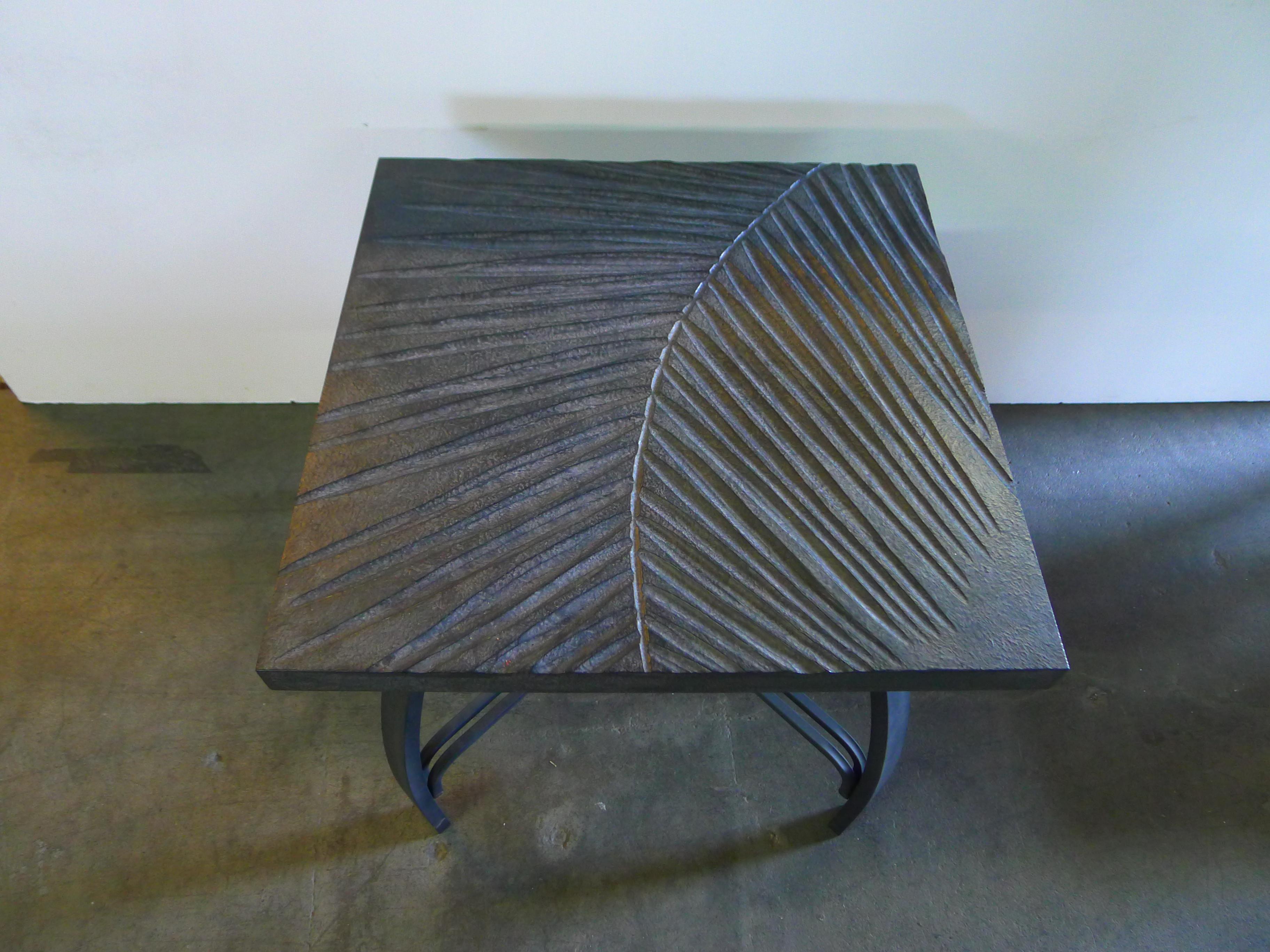 Hand carved fossilized frond side table that can also be customized as a cocktail table. By order. Each tabletop is hand carved wood in gray slate coloration, and with iron base. Also can be placed outdoors in undercover location. This is a