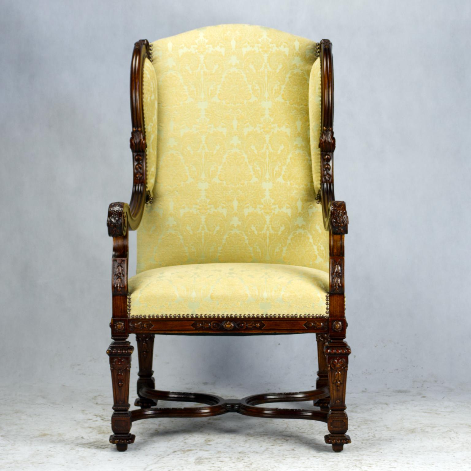 French Louis XIV walnut wingback armchair is a study in stately elegance, with extraordinary comfort. Gracefully contoured wingbacks with double-scrolled frameworks cradle one in luxury, with a generous seat below defined by the contoured and finely