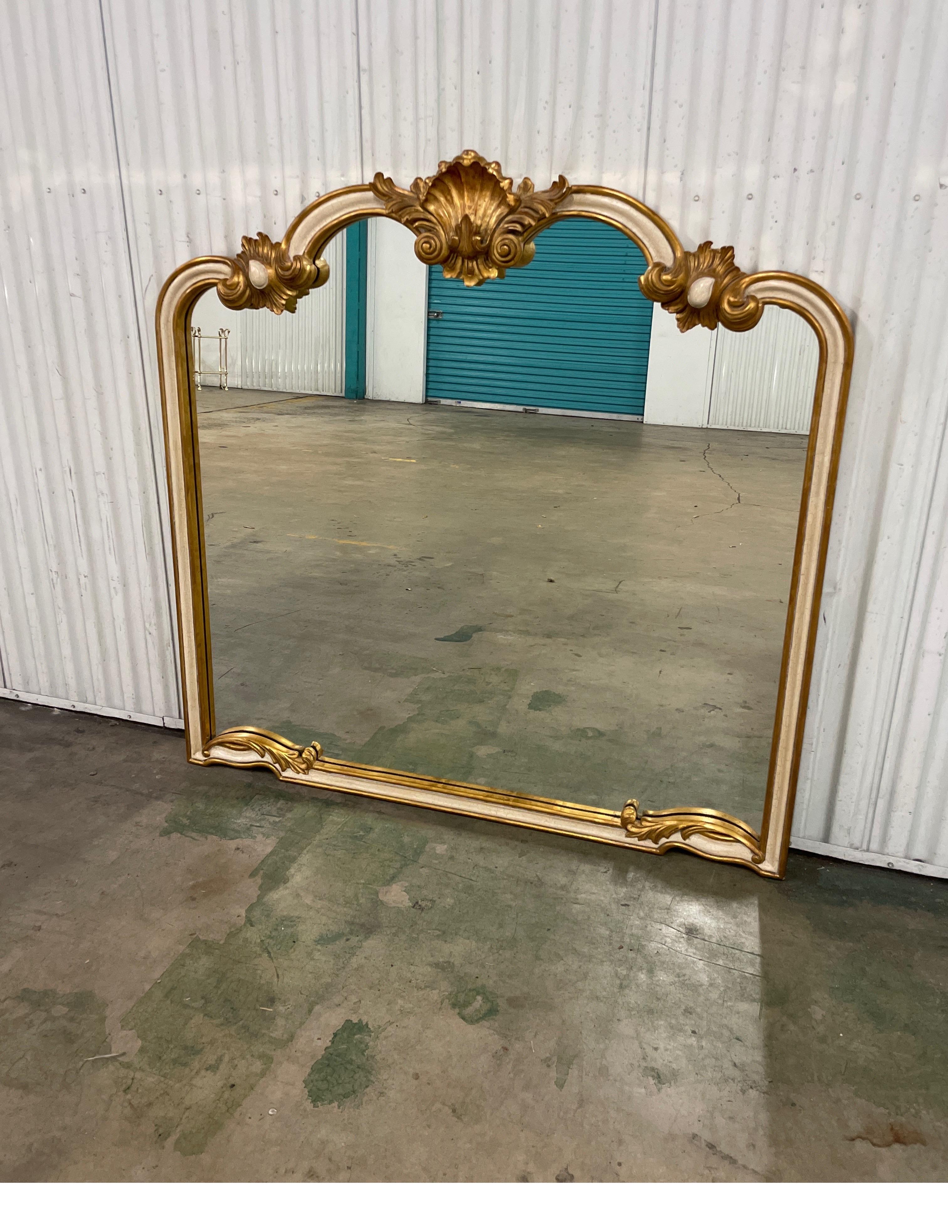 Beautifully carved, gilded and painted mirror by Harrison & Gil. Wonderful carved details with a large shell at the top. This mirror will be a standout wherever you place it. Will work great over a fireplace, dining room buffet, console or a sofa.